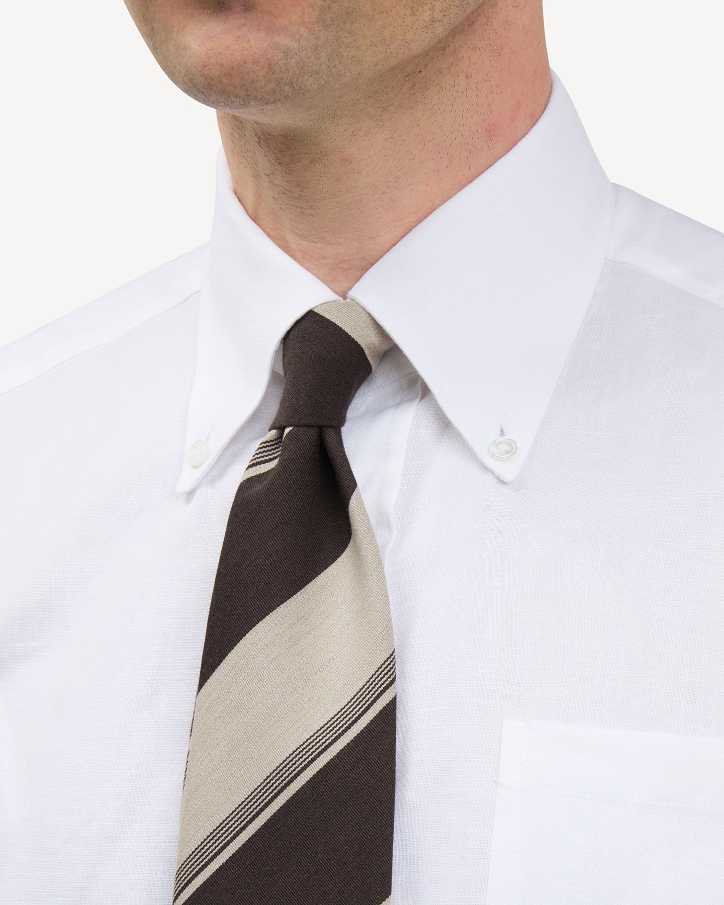 Man wearing a white button down shirt and brown and beige stripe wool cotton tie