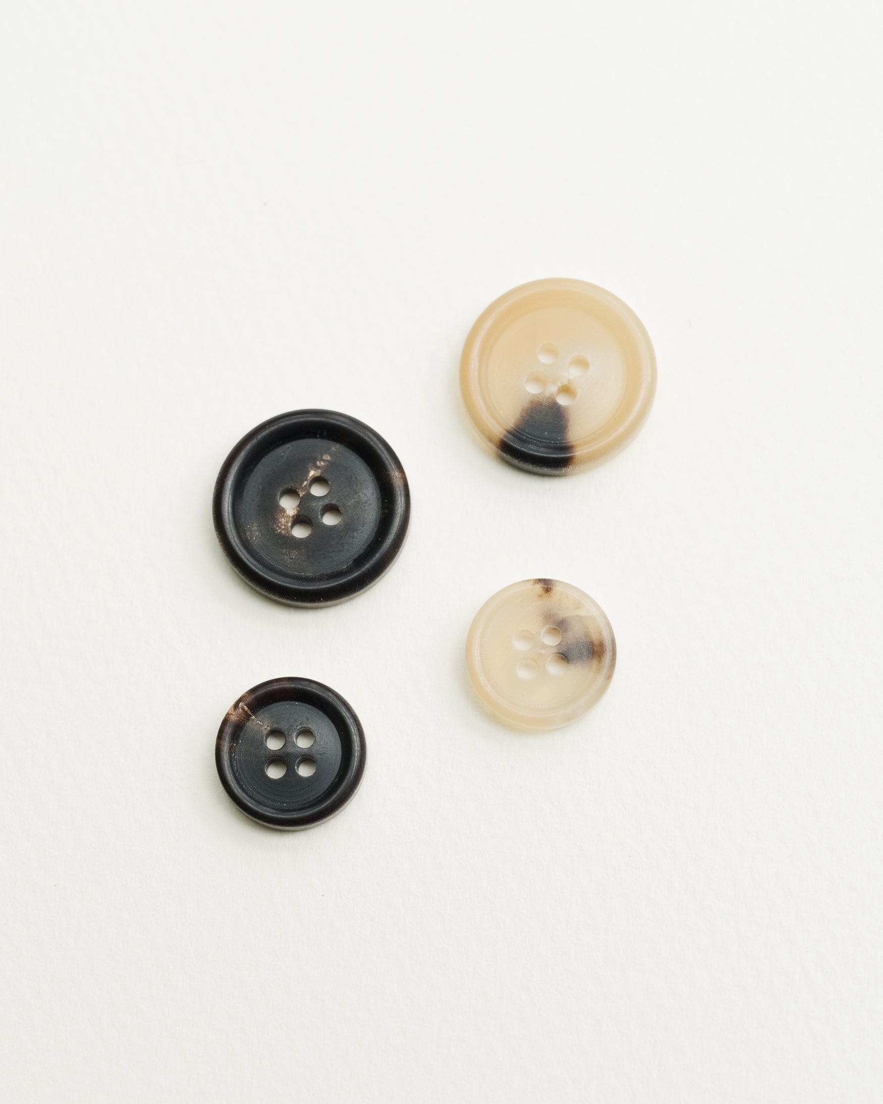 Selection of light brown and dark brown horn buttons displayed — options for made-to-measure tailoring by Besnard.