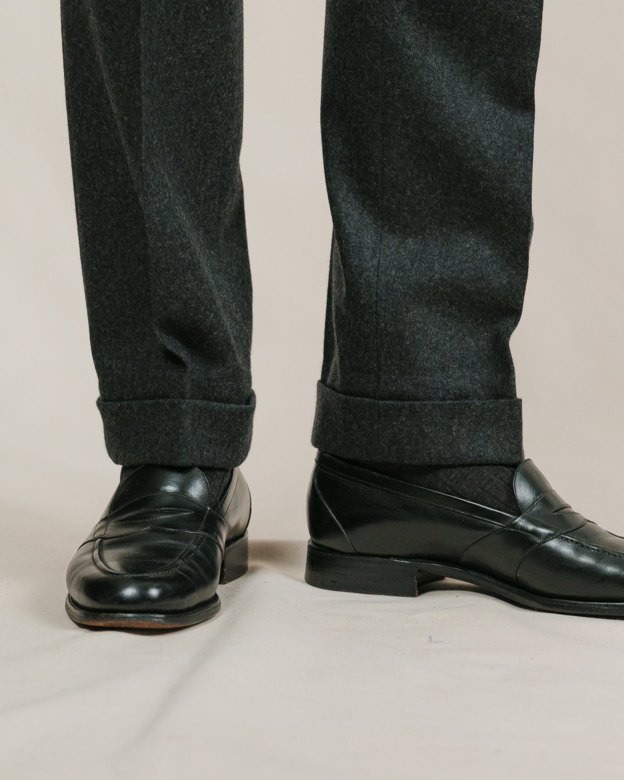 Zoom on charcoal flannel trousers, charcoal socks and black leather full strap penny loafers