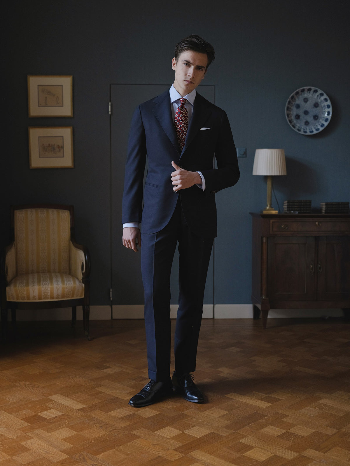 Man wearing a navy hopsack suit, light blue spread collar shirt and red medallion ancient madder tie