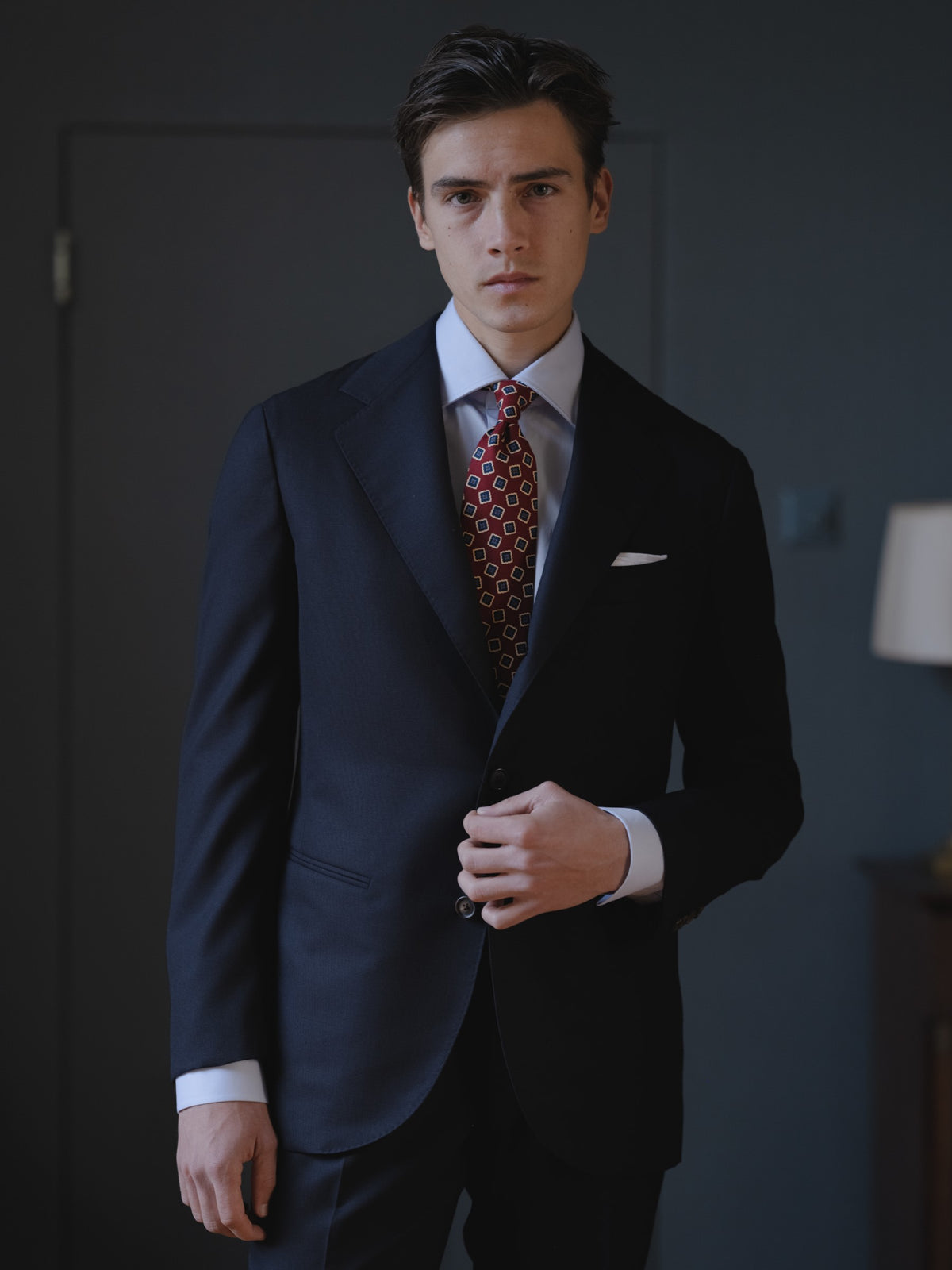 Man wearing a navy hopsack suit, light blue spread collar shirt and red medallion ancient madder tie