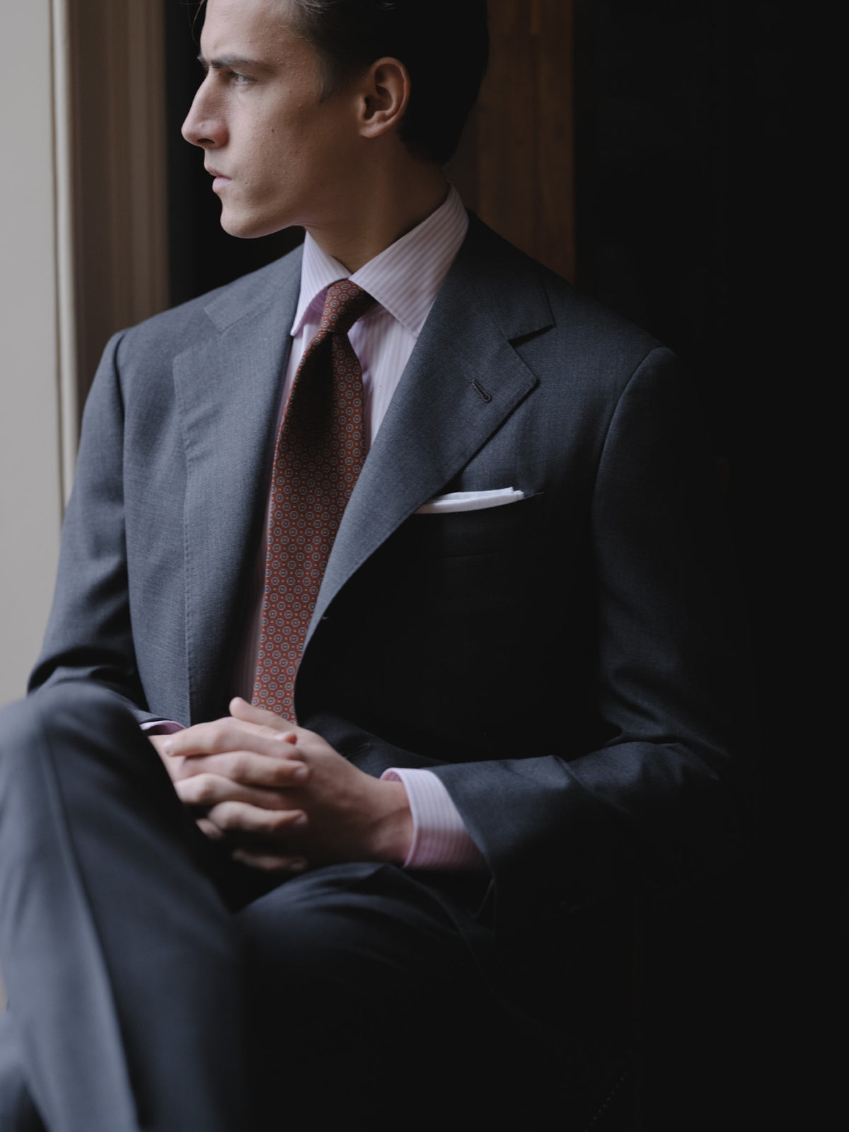 Man wearing a mid grey sharkskin suit, pink bengal stripe spread collar shirt and red pattern ancient madder tie