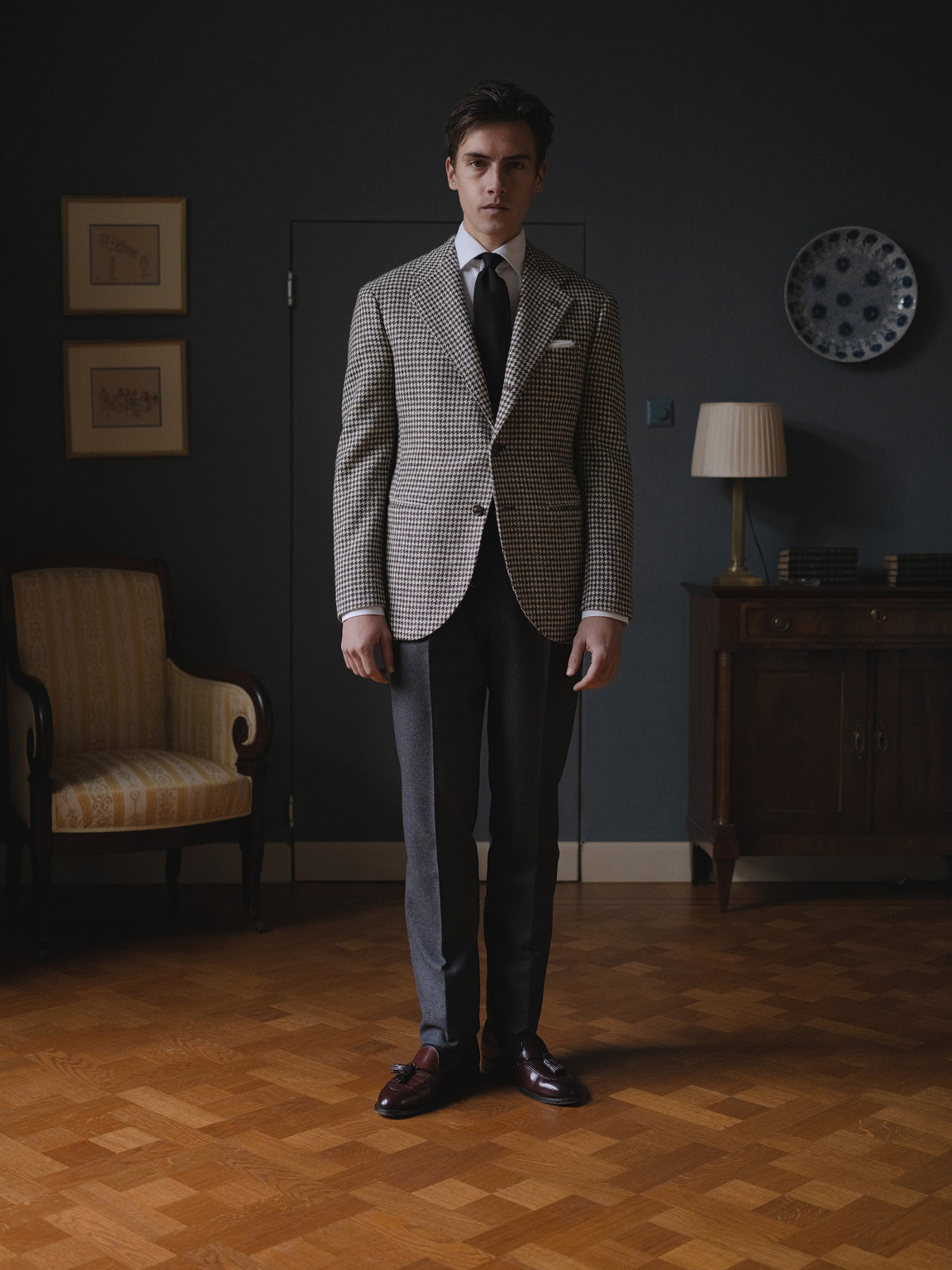 Man wearing a black white houndstooth sport coat, dark grey flannel trousers, a white shirt and a black garza grossa grenadine tie