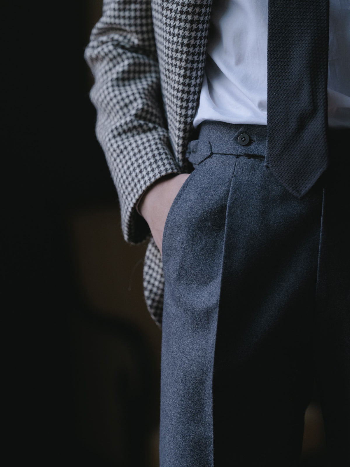 Man wearing a black white houndstooth sport coat, dark grey flannel trousers, a white shirt and a black garza grossa grenadine tie