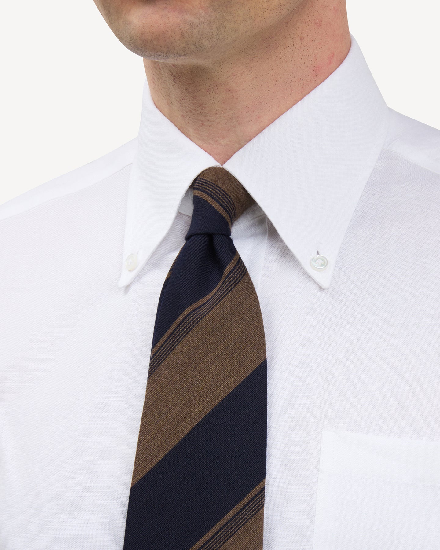 Man wearing a white button down shirt and navy and mid brown stripe wool cotton tie