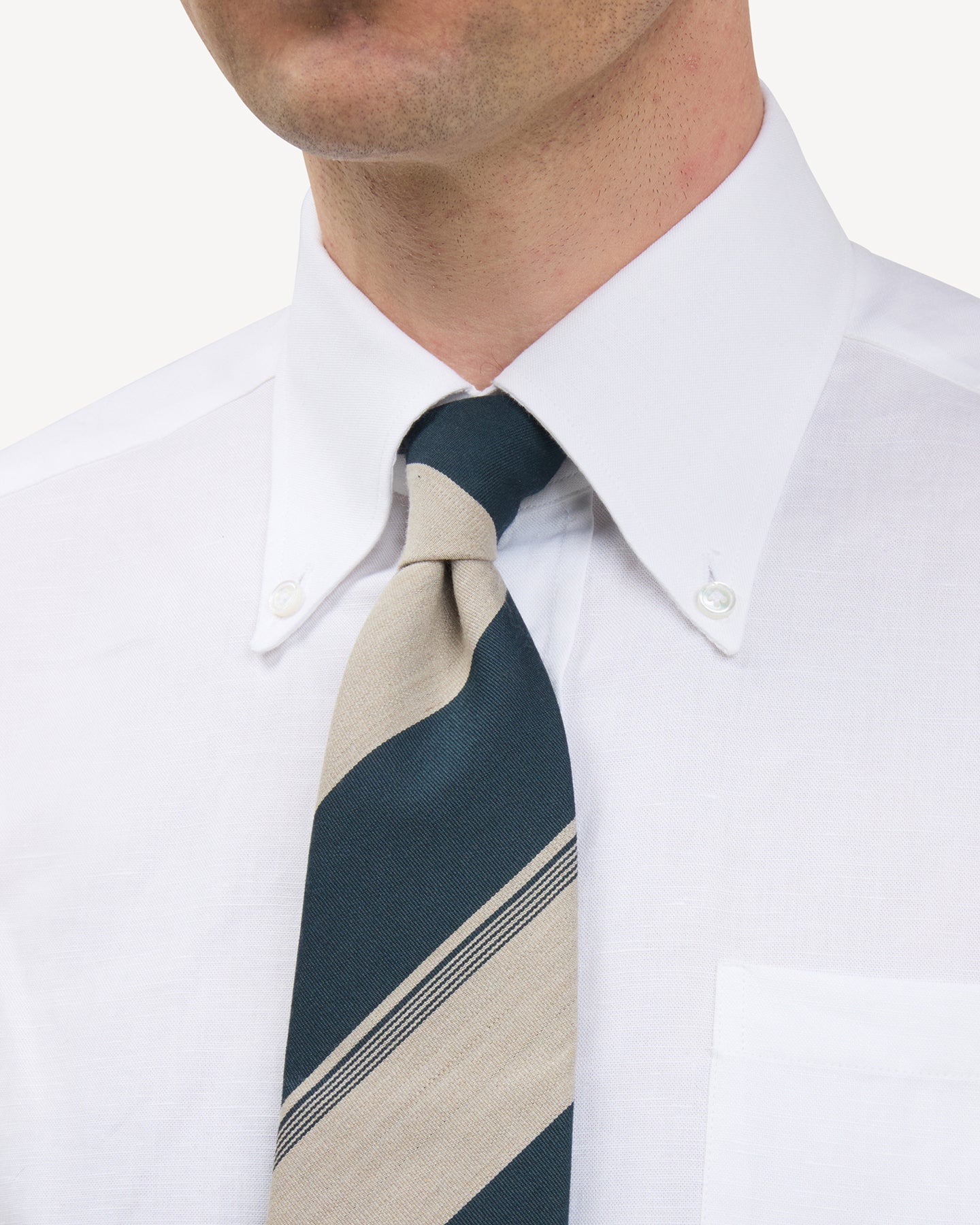 Man wearing a white button down shirt and petrol and beige stripe wool cotton tie