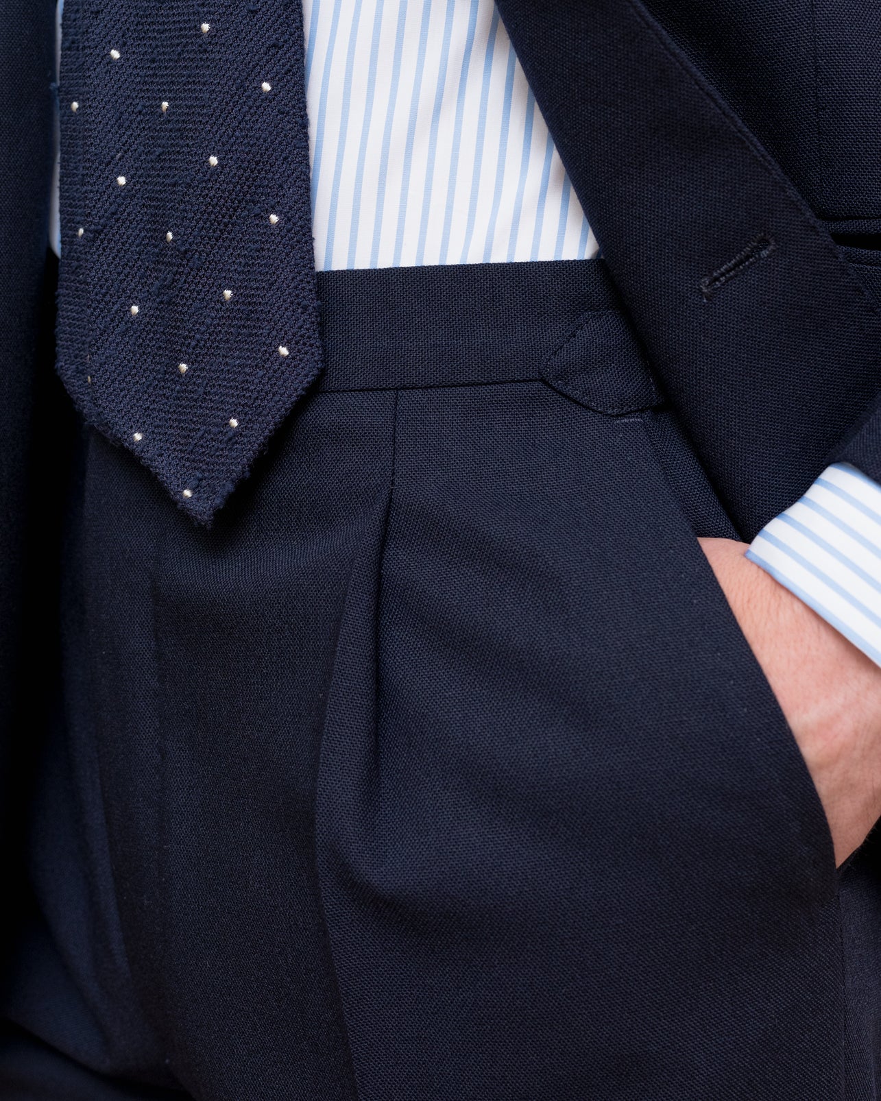 Man wearing a navy high twist suit, blue striped poplin shirt and navy polkadot shantung silk tie