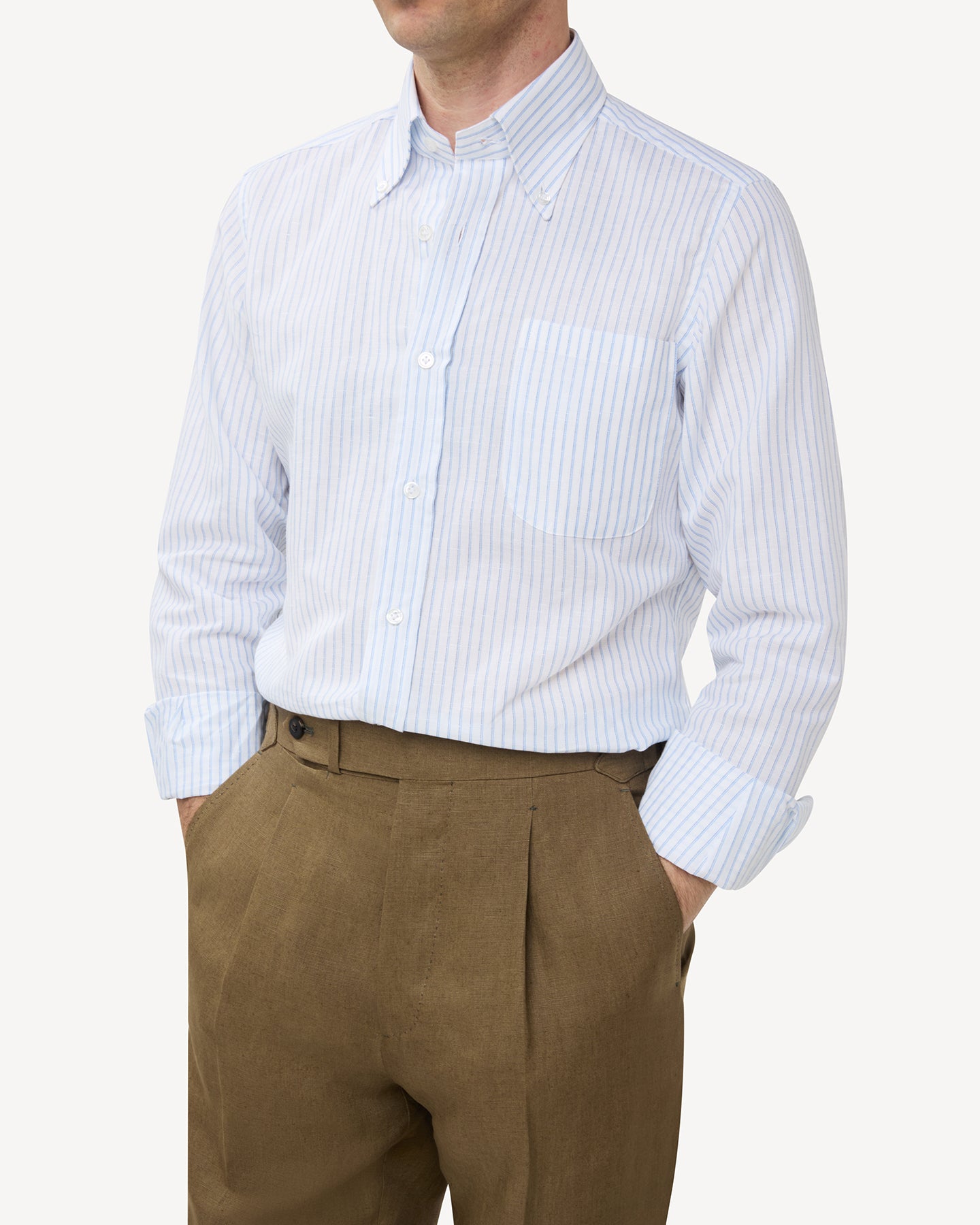 Man wearing blue stripe summer OCBD shirt with olive brown linen trousers