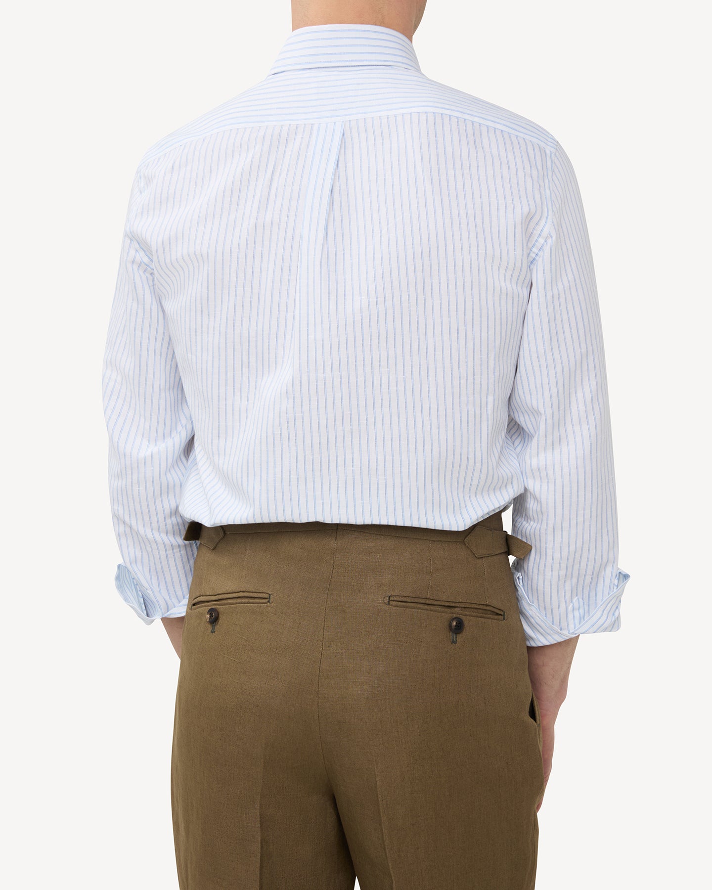 Man wearing blue stripe summer OCBD shirt with olive brown linen trousers