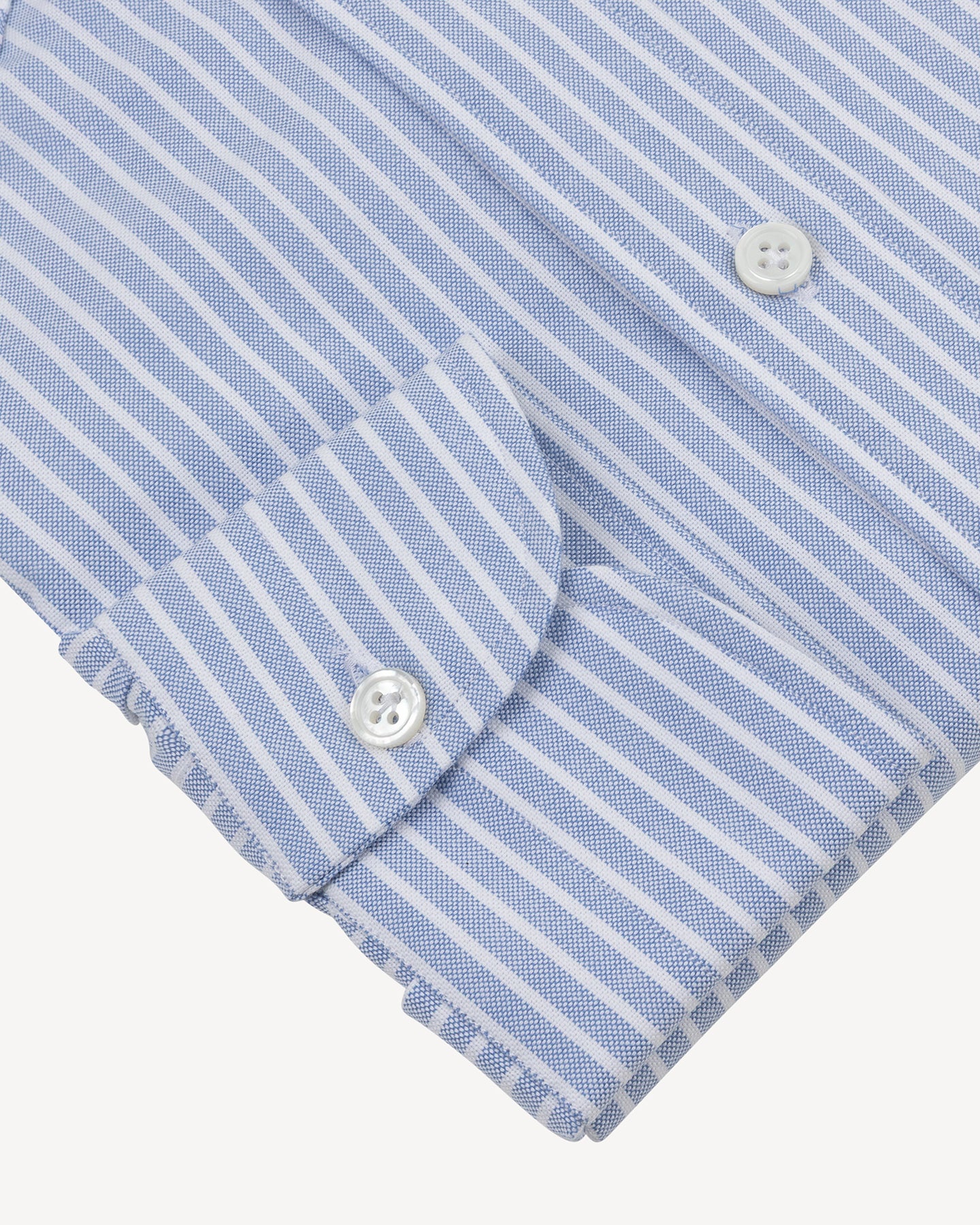 Close-up of the cuff of a blue and white striped shirt