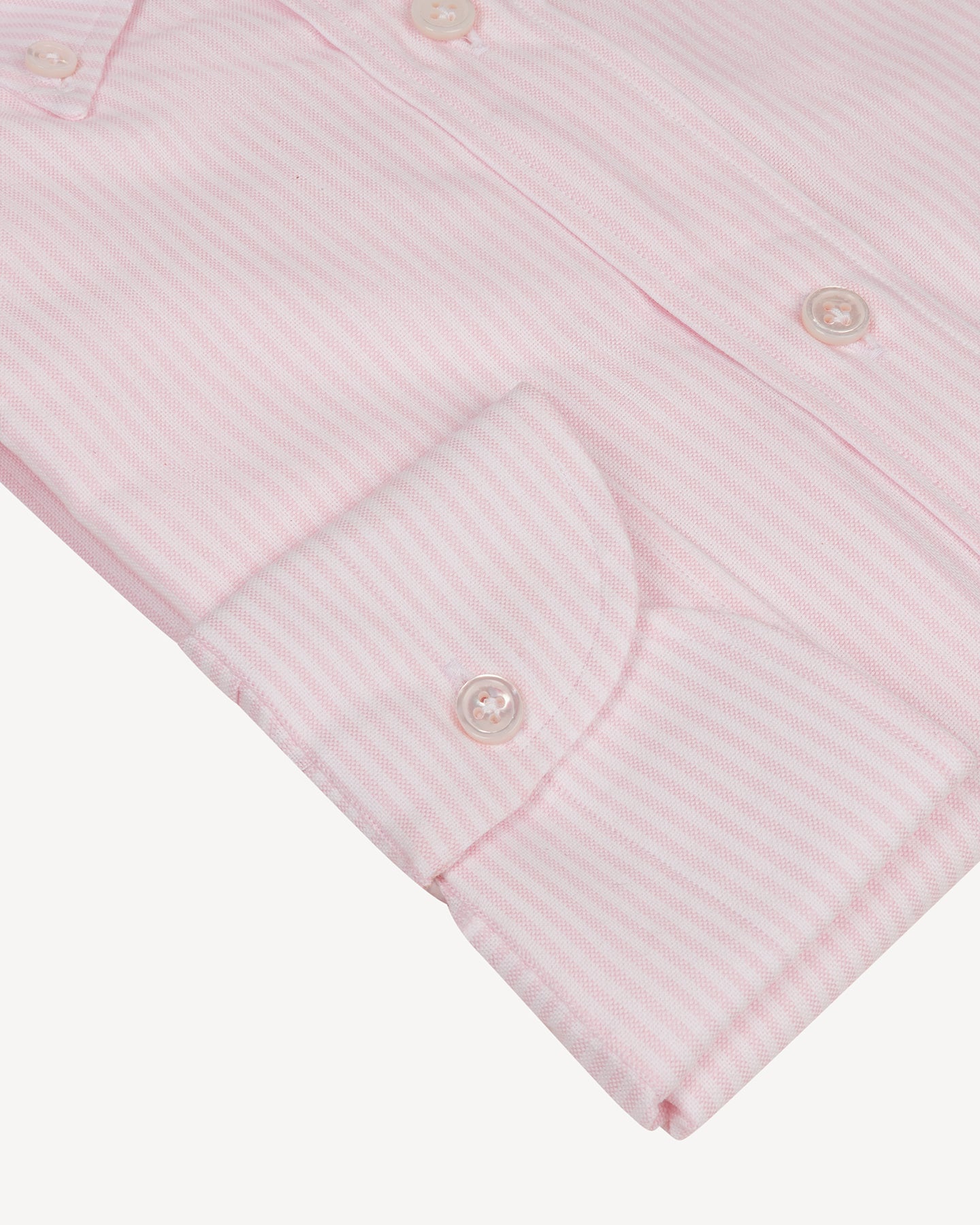 A close up of a pink striped shirt with single cuffs