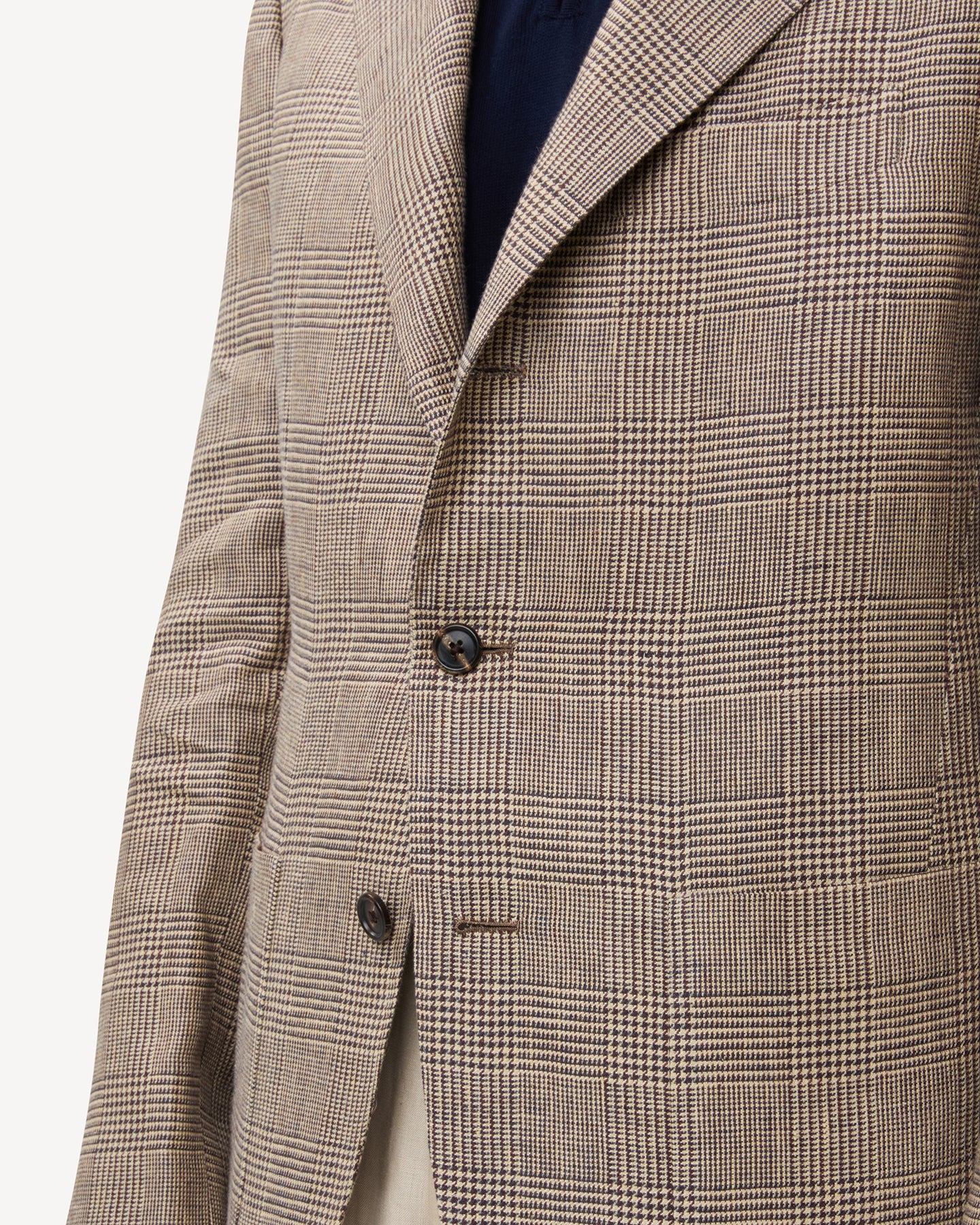 The patch pocket of a brown linen Prince of Wales sport coat