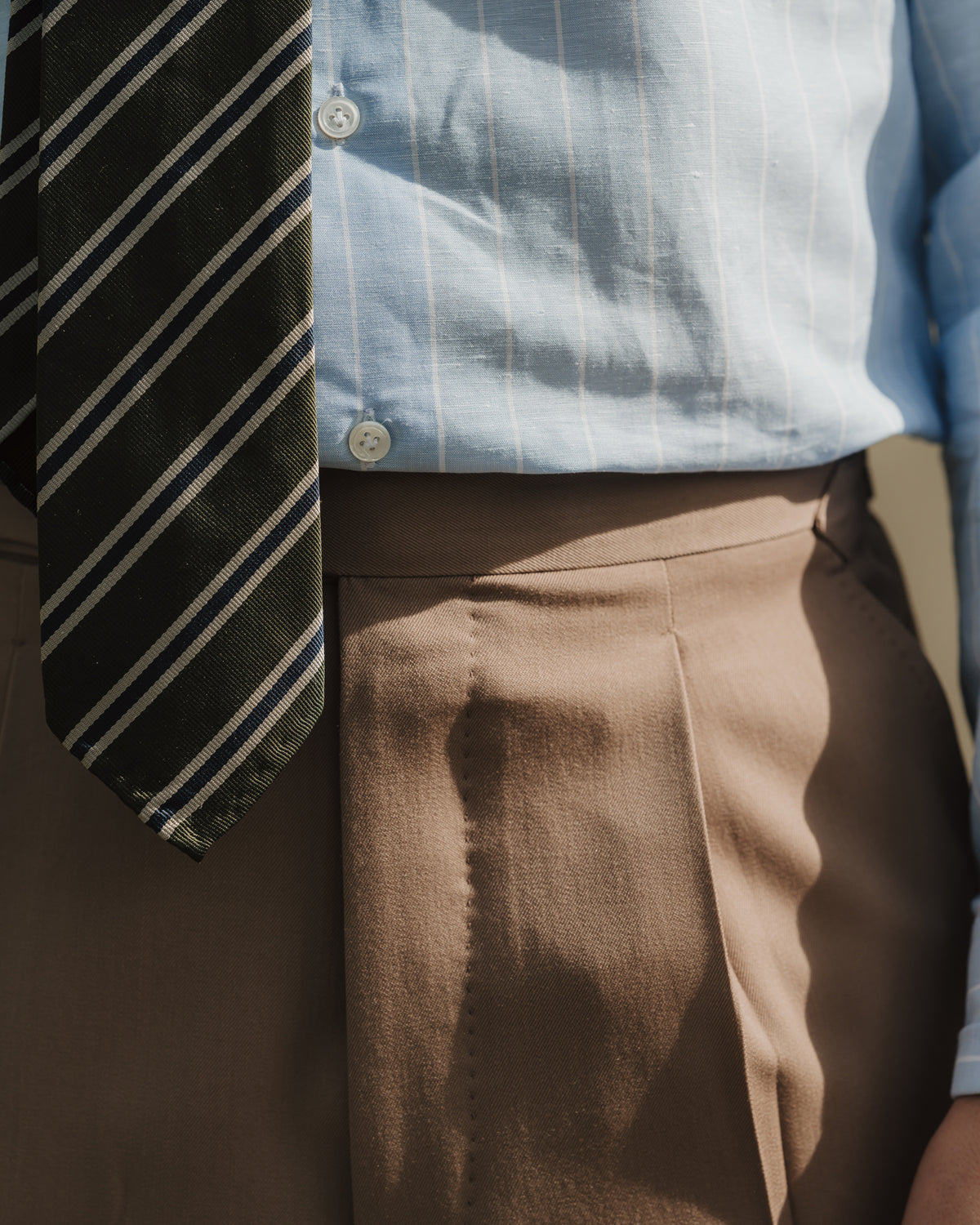 Man wearing tan gabardine suit, a blue reverse stripe cotton linen shirt and a green regimental stripe repp tie