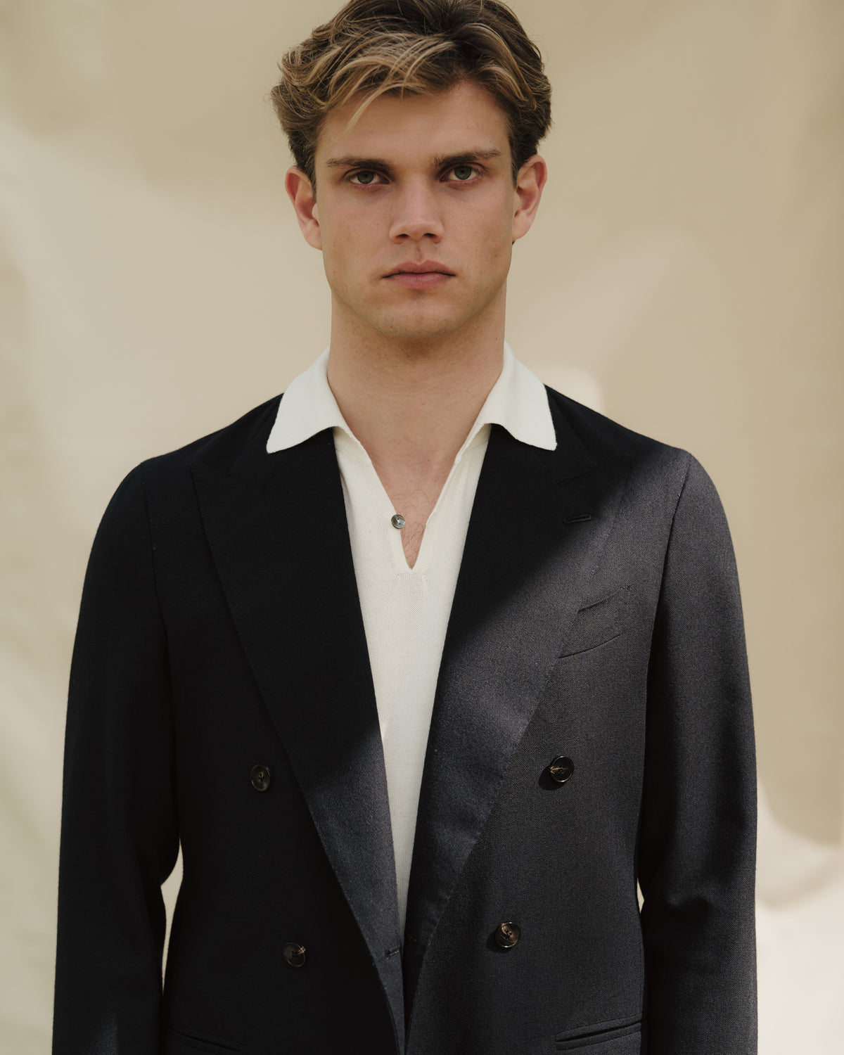 Man wearing stone cotton drill shorts and navy double breasted jacket