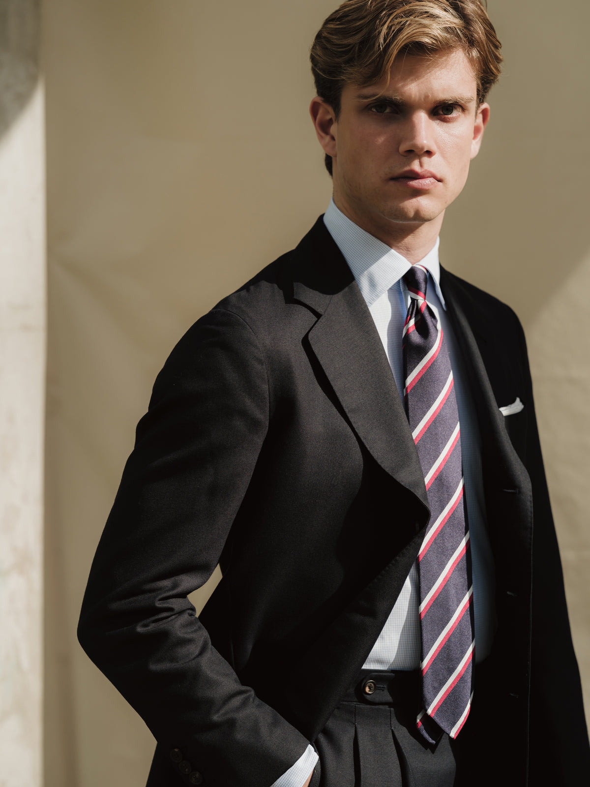 Man wearing navy hopsack suit, blue fine graph check poplin shirt and navy red regimental stripe repp tie
