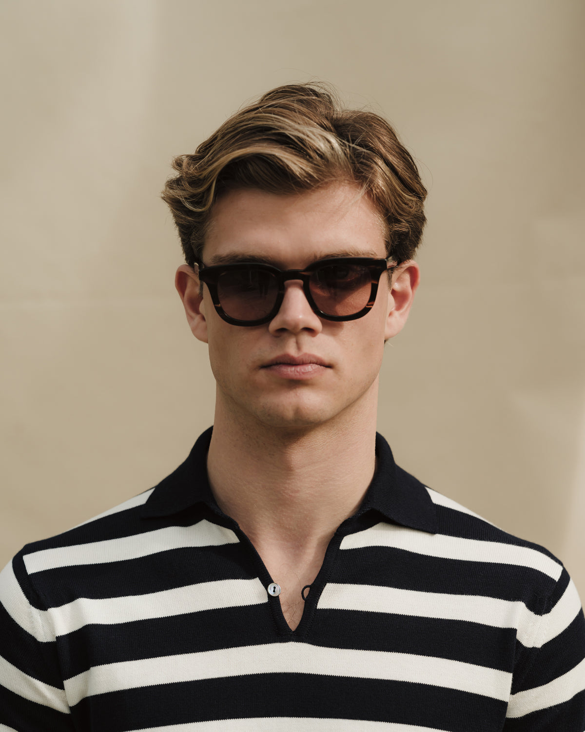 Man wearing a white navy nautical stripes skipper polo and sunglasses