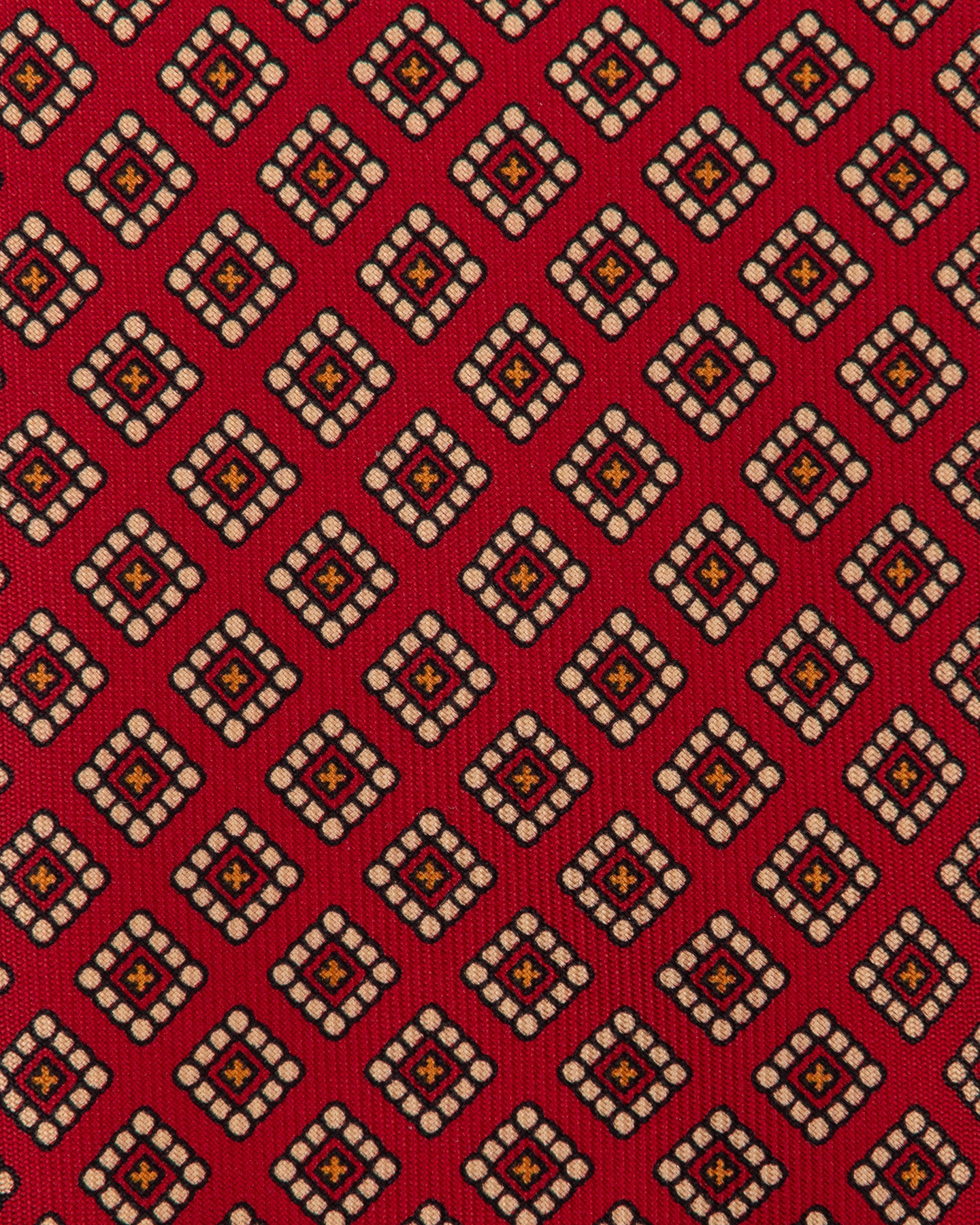 Red Ancient Madder tie with small medallion pattern in shades of cream, orange and black.