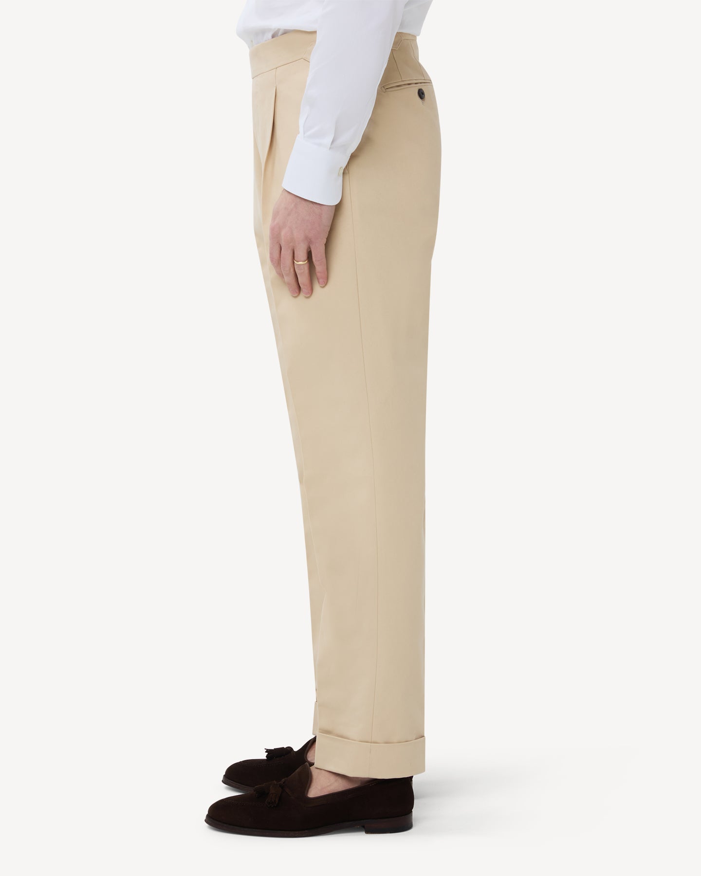 The side of cream cotton trousers with single pleats and side adjusters