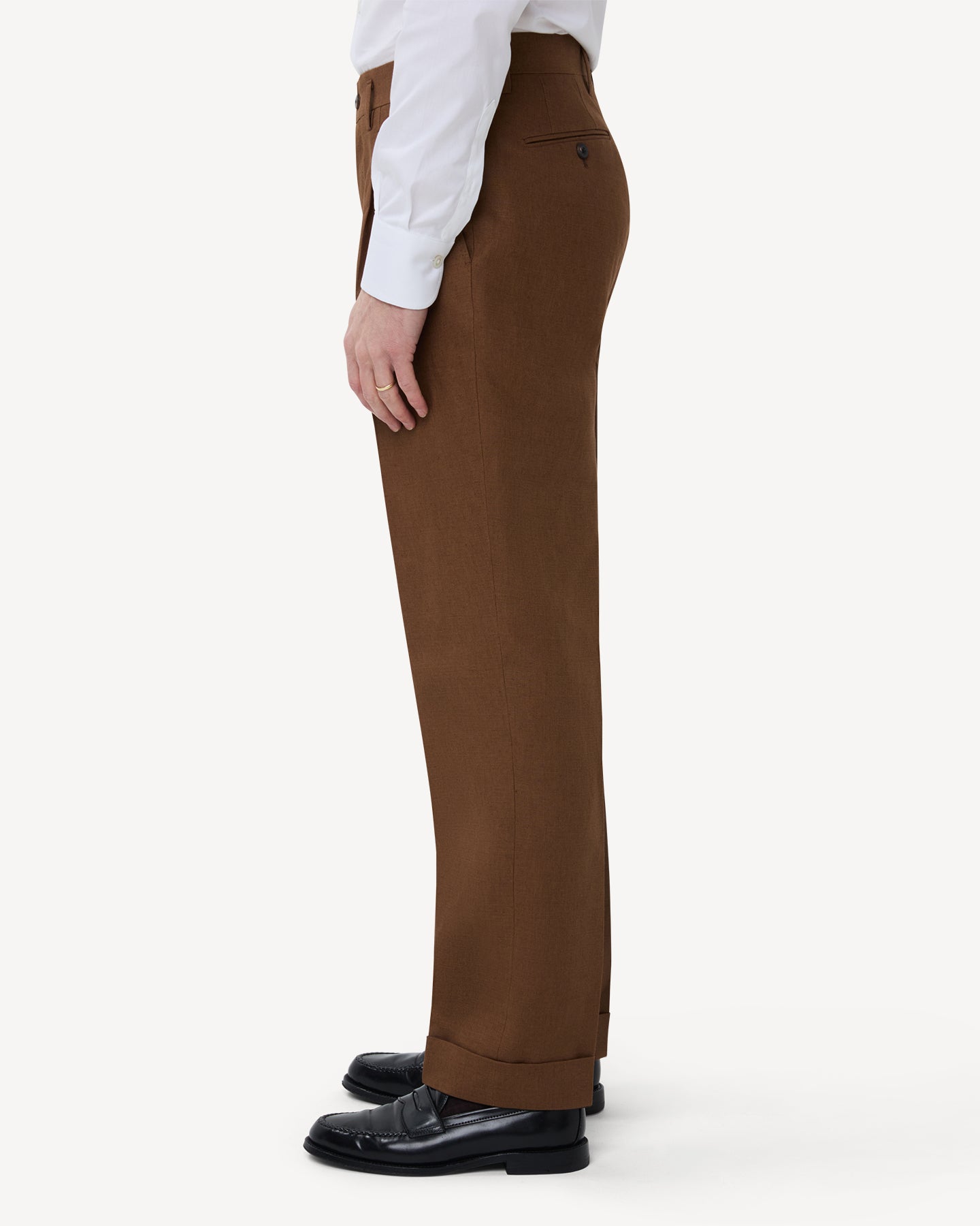 The side of dark tan linen trousers with double pleats and belt loops