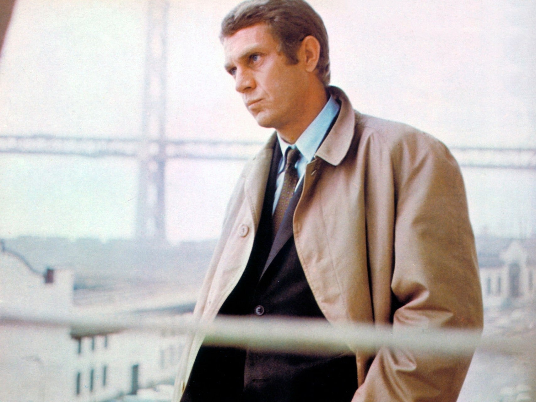 Steve McQueen wearing a suit, raglan rain coat and ancient madder tie in the movie Bullitt