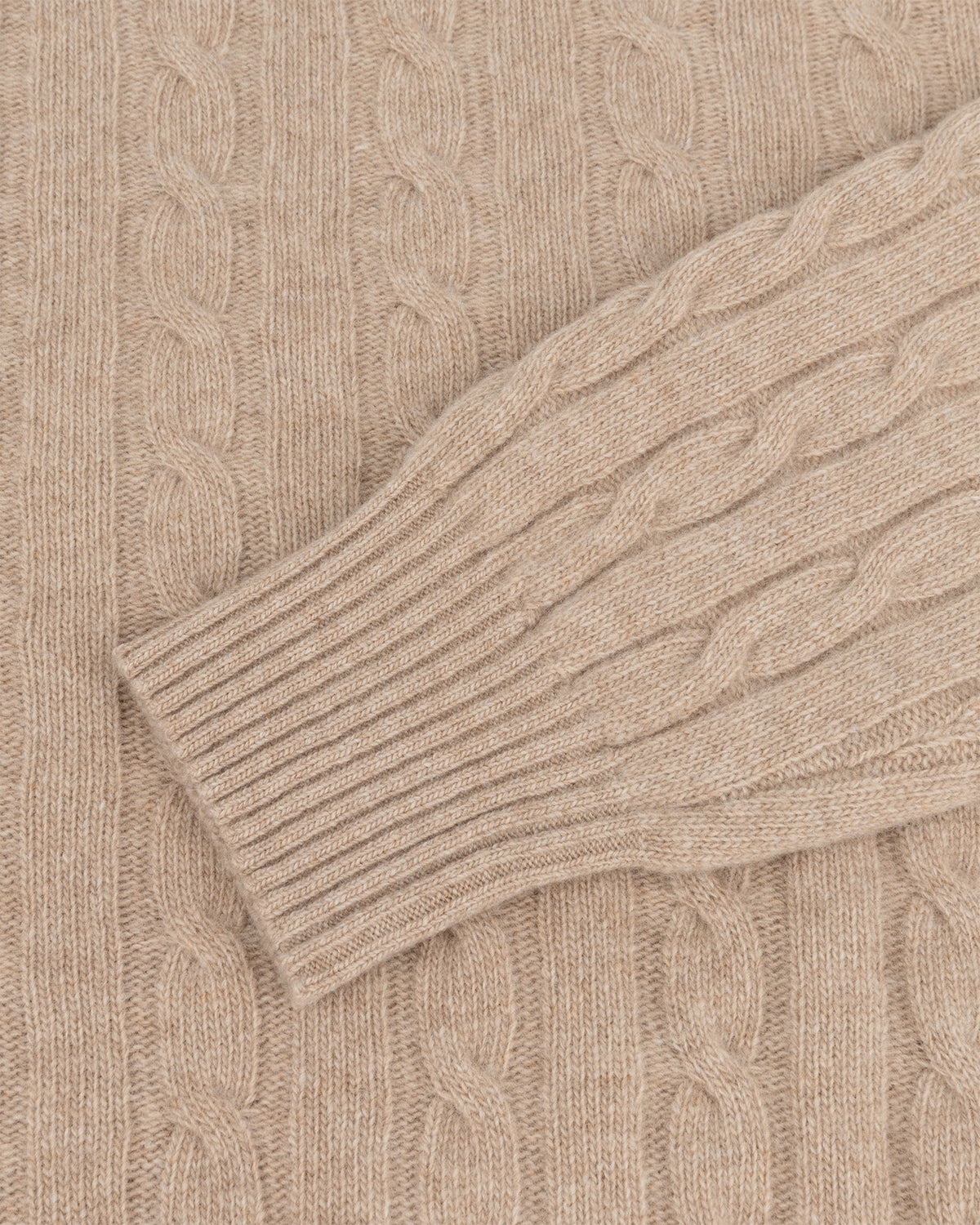 Geribbelde manchet en kabelgebreide mouw van een beige trui van wol en kasjmier