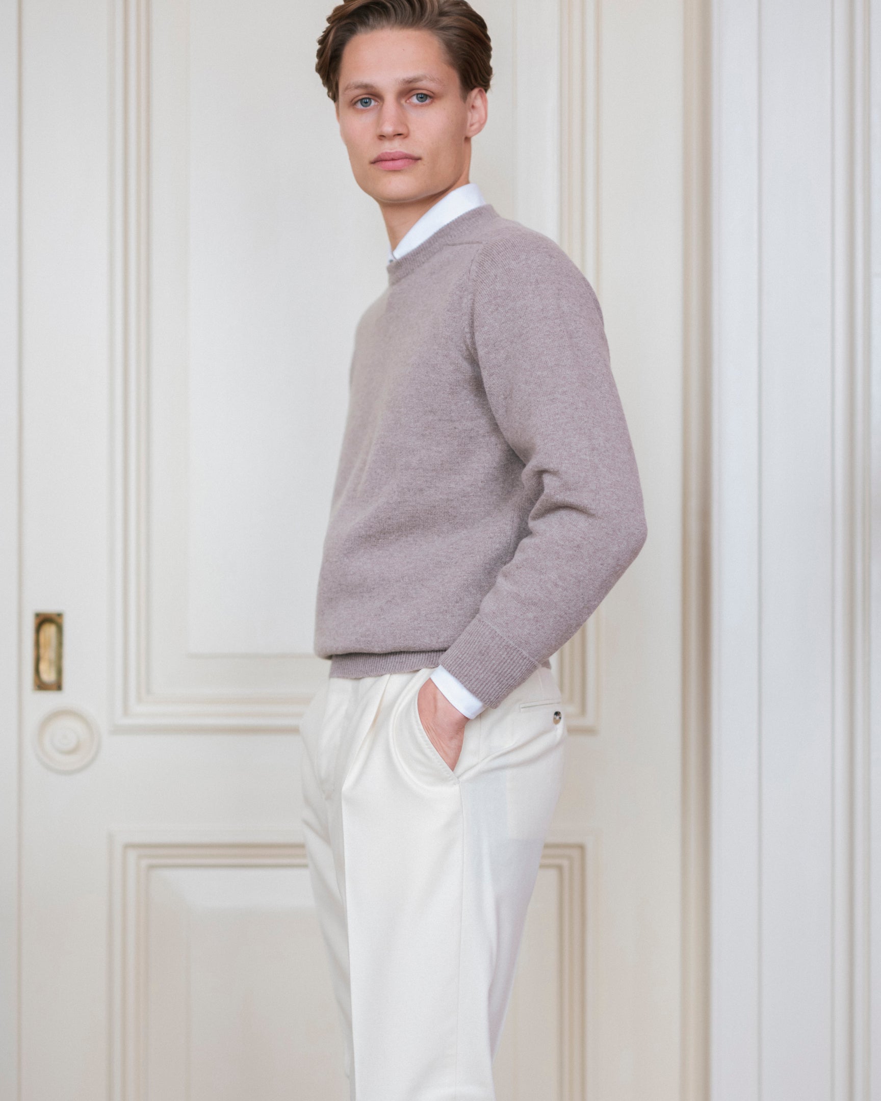 Man wearing cream Fox Brothers cricket flannel trousers, a white dress shirt and a light grey crewneck sweater