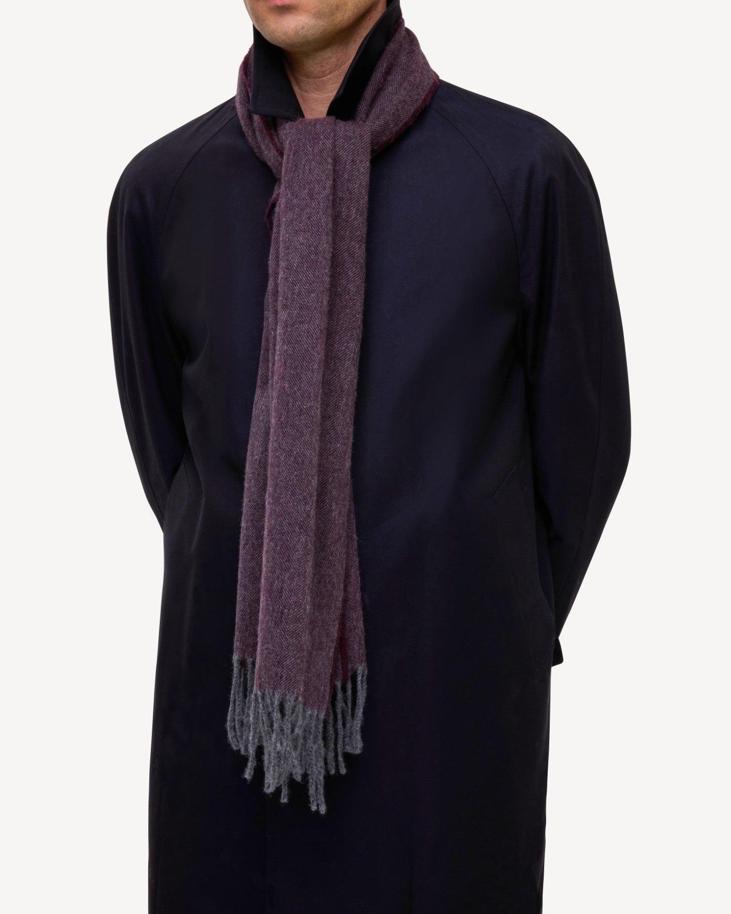 Man wearing a cashmere scarf in aubergine/eggplant with herringbone design