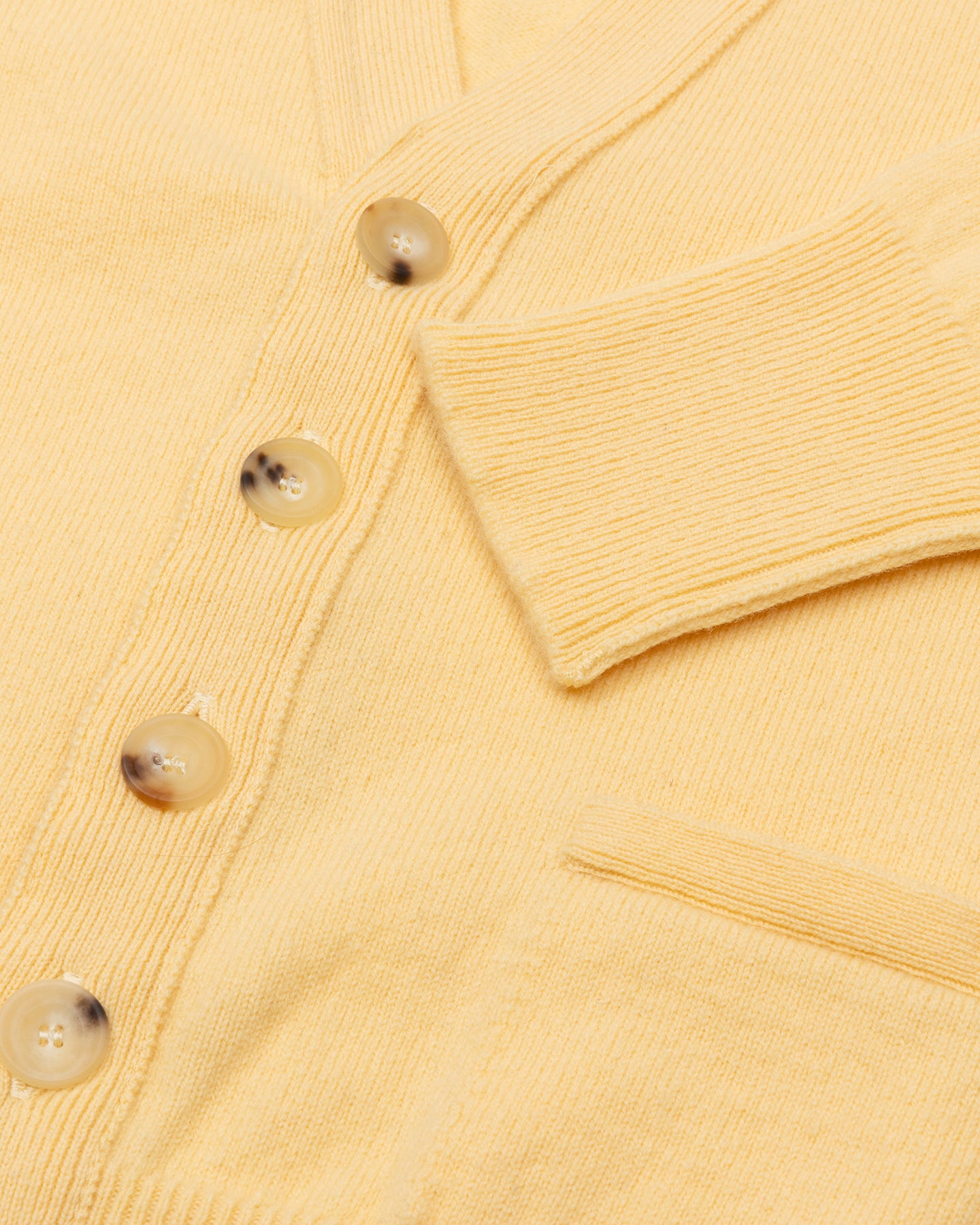 A yellow lambswool cardigan with horn buttons and front pockets