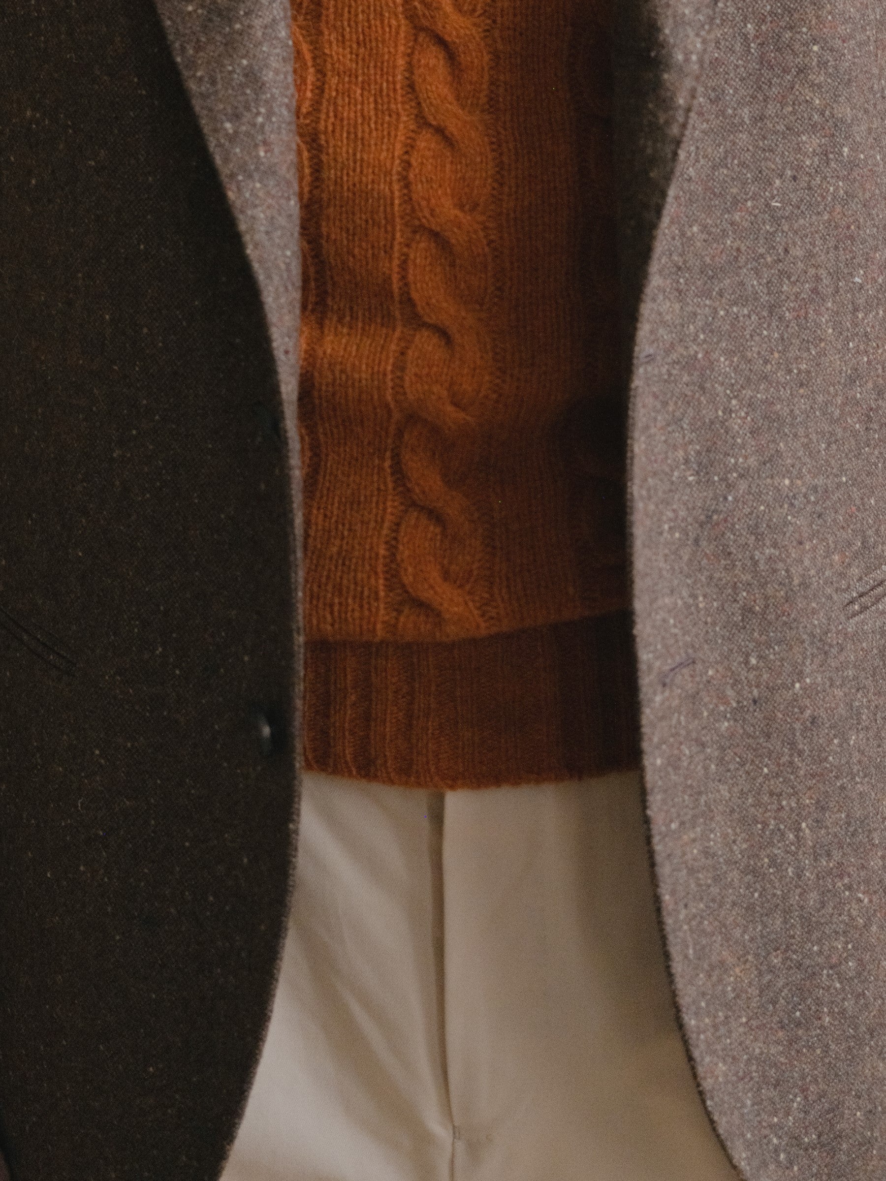 Man wearing a brown donegal tweed sport coat, burnt orange shetland sweater and cream cotton drill trousers