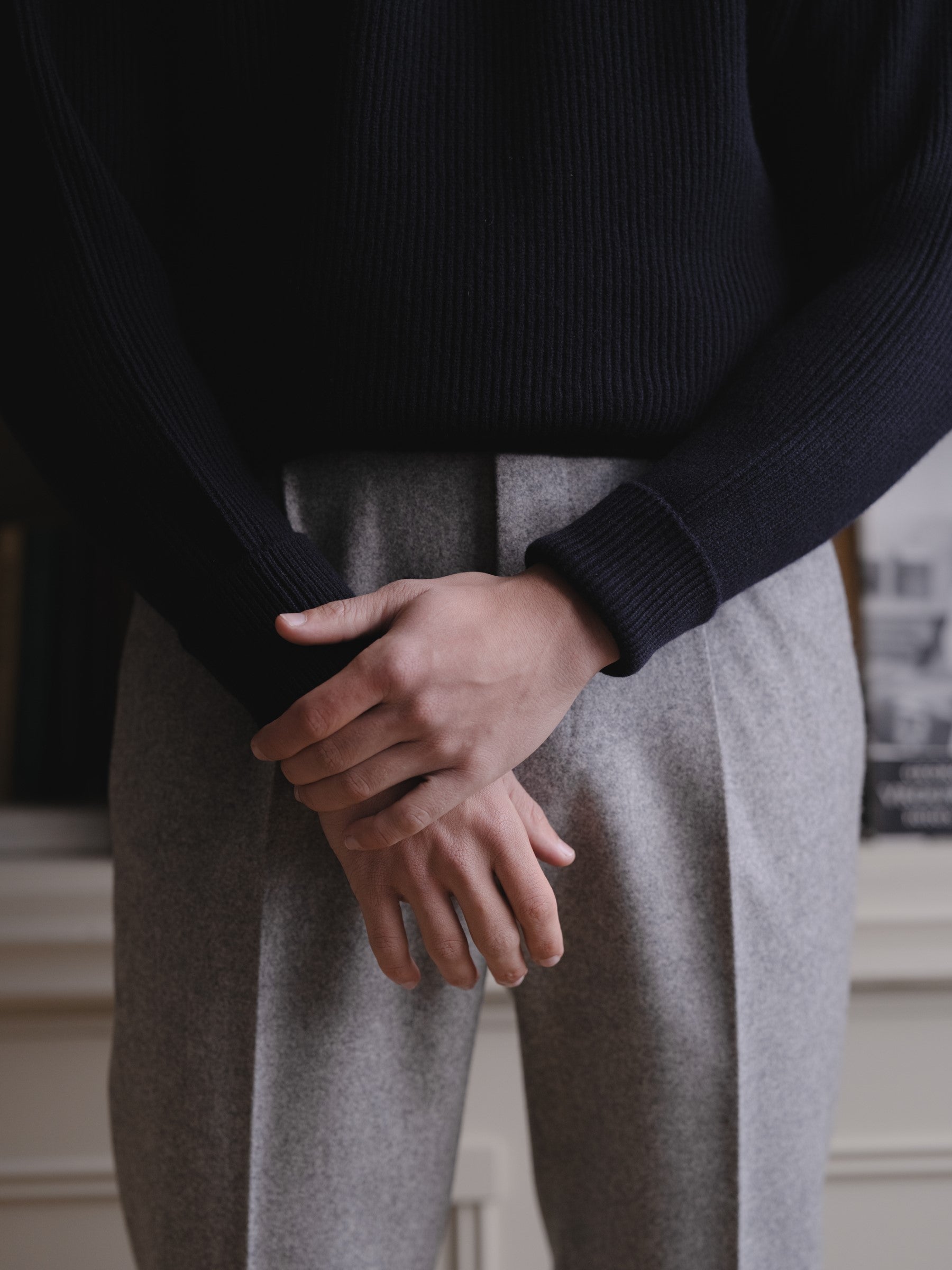 Man wearing a navy ribbed lambswool sweater and light grey flannel trousers