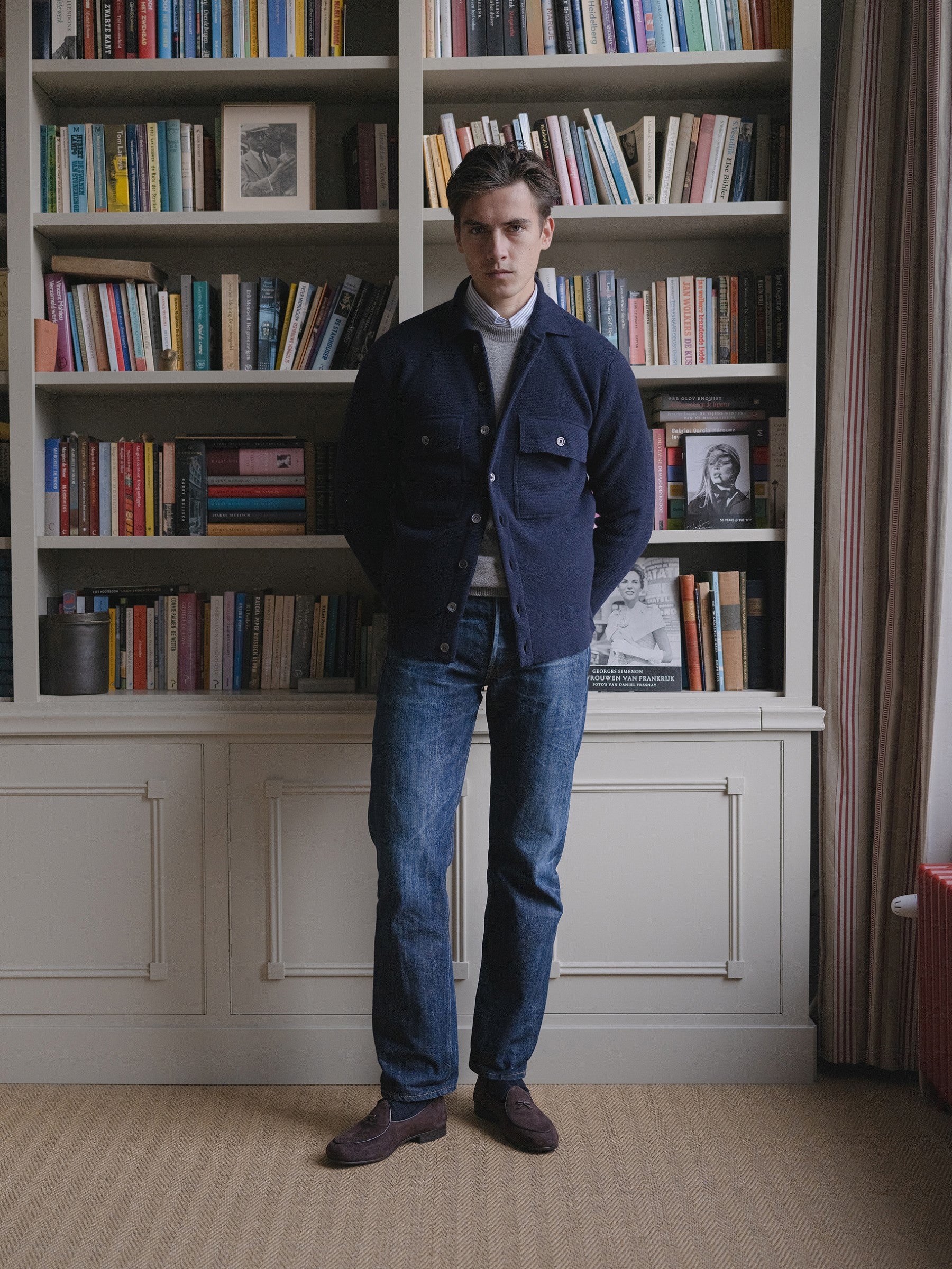 Man wearing a navy two pocket overshirt, stone washed jeans, grey crewneck and striped shirt