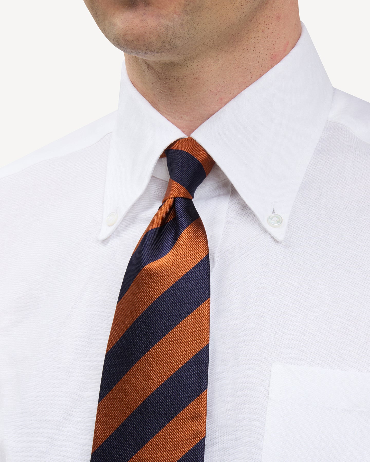 Man wearing white button down shirt and navy orange striped repp tie