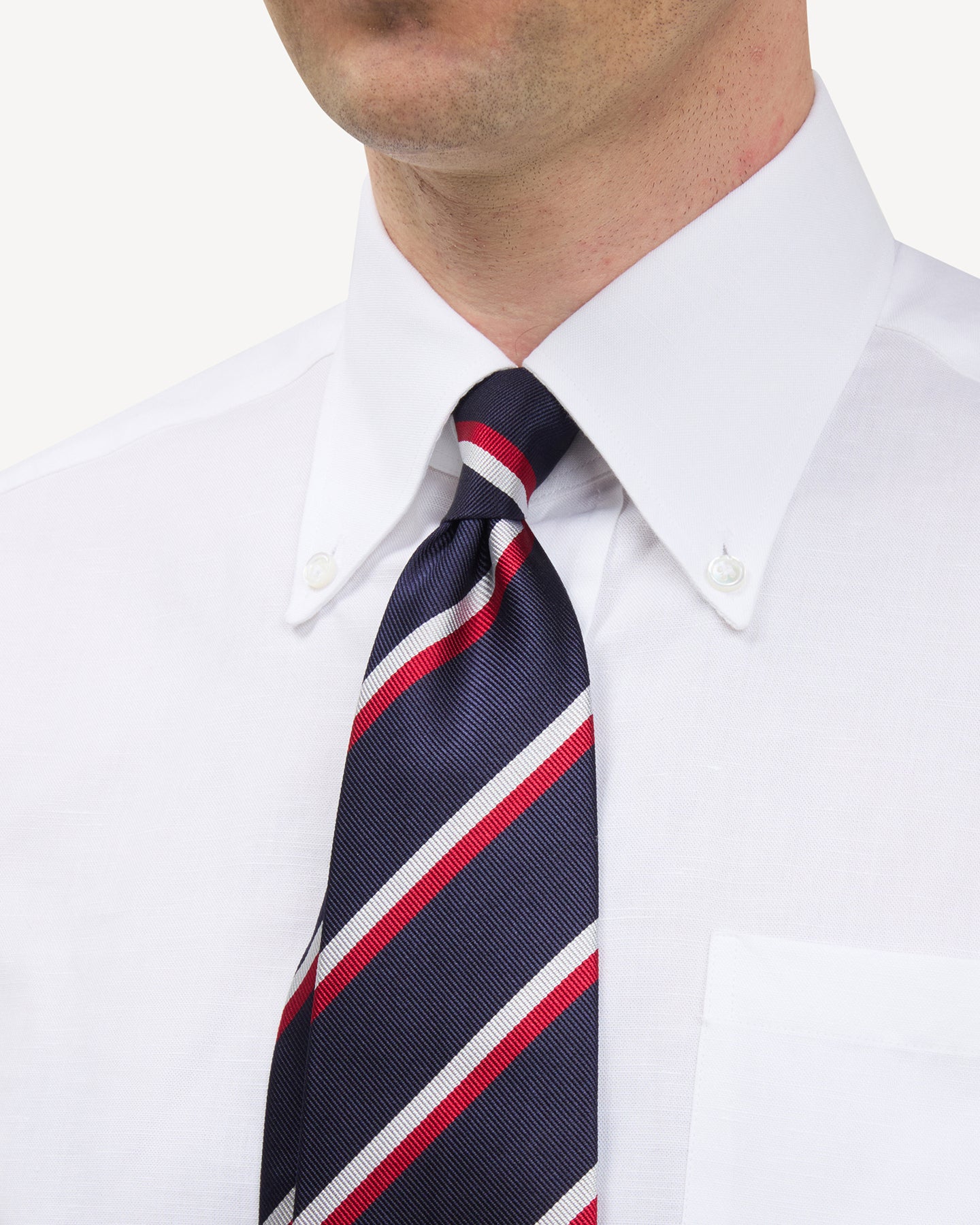 Man wearing a white button down shirt and a navy, red and white regimental stripe repp tie