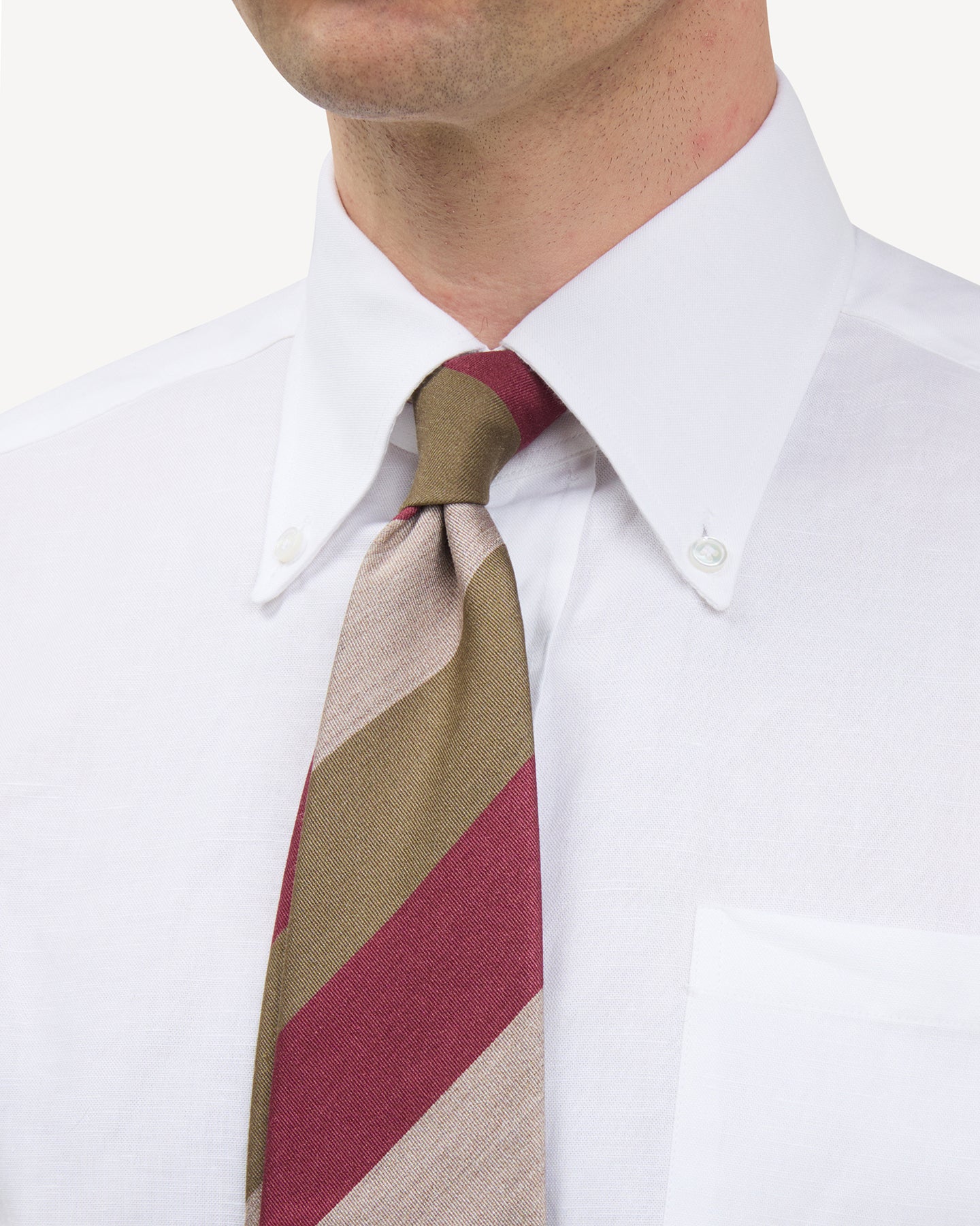 Man wearing a white button down shirt and a raspberry, beige and olive block stripe mogador tie