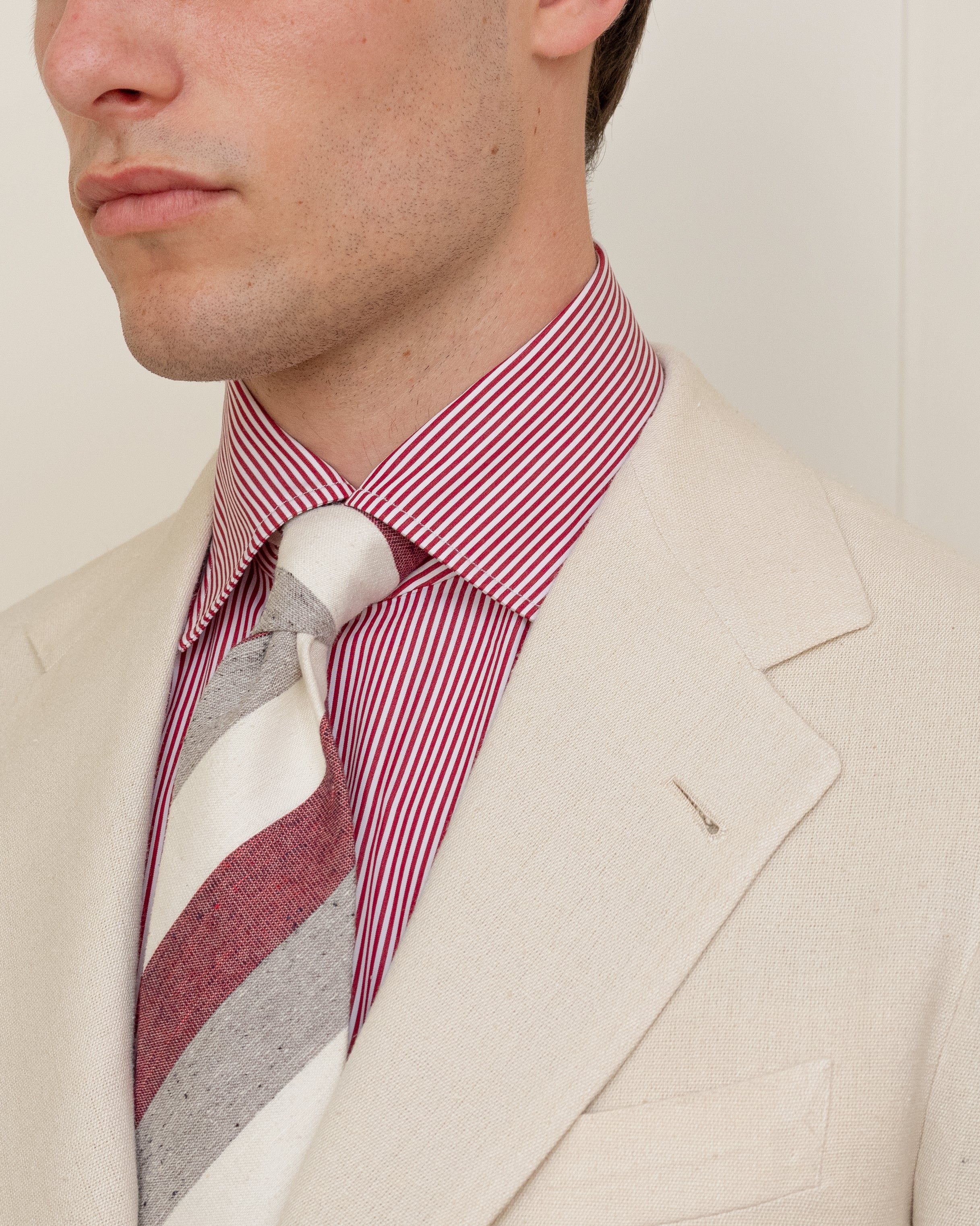 Man wearing a cream silk sport coat, a red bengal stripe spread collar shirt and red block stripe tie