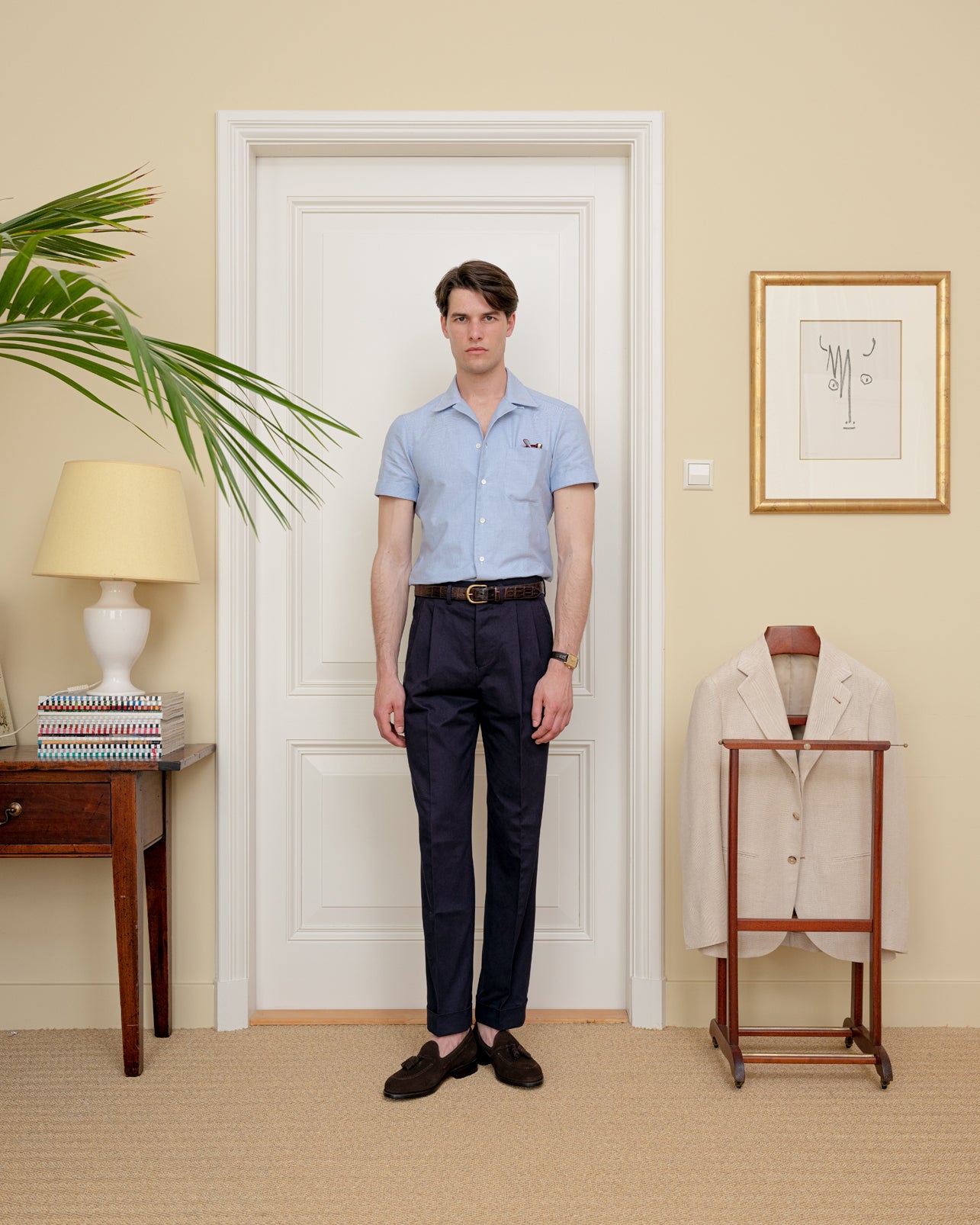 Man wearing a pair of navy cotton trousers and a blue camp collar shirt