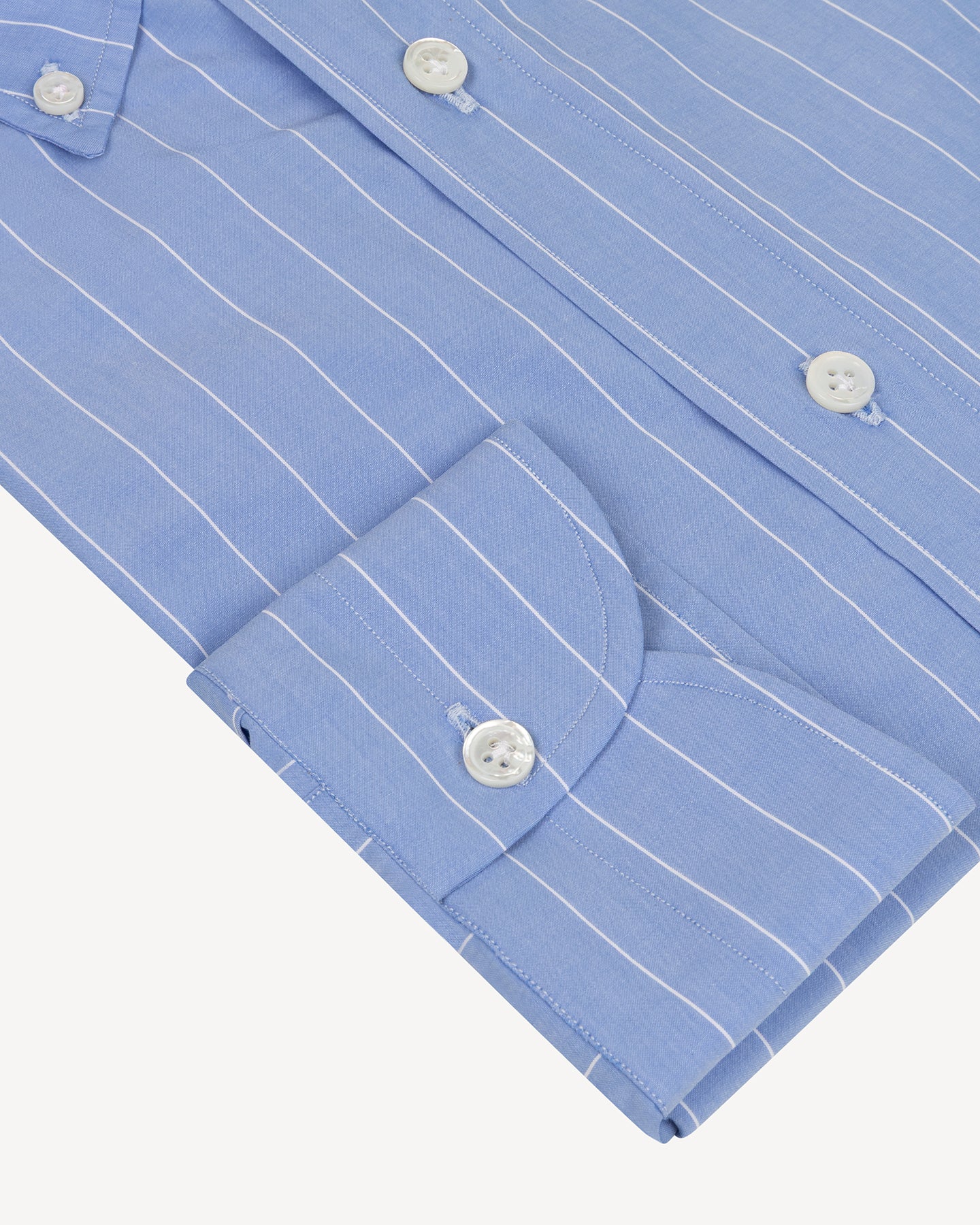 Close-up of a blue striped shirt with mother of pearl buttons on a white background