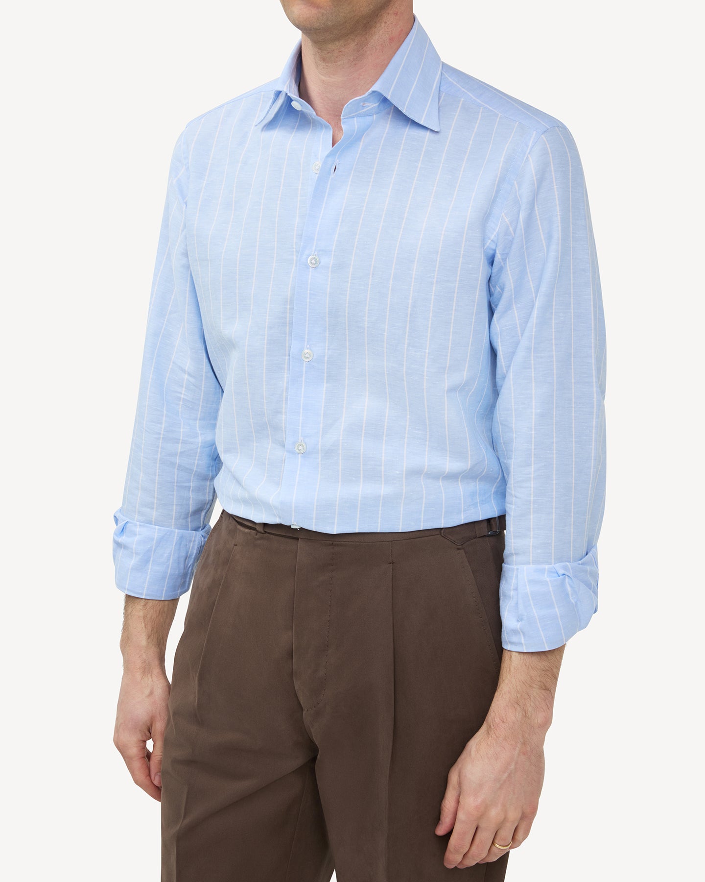Man wearing a light blue reverse stripe cotton linen shirt and tobacco cotton trousers