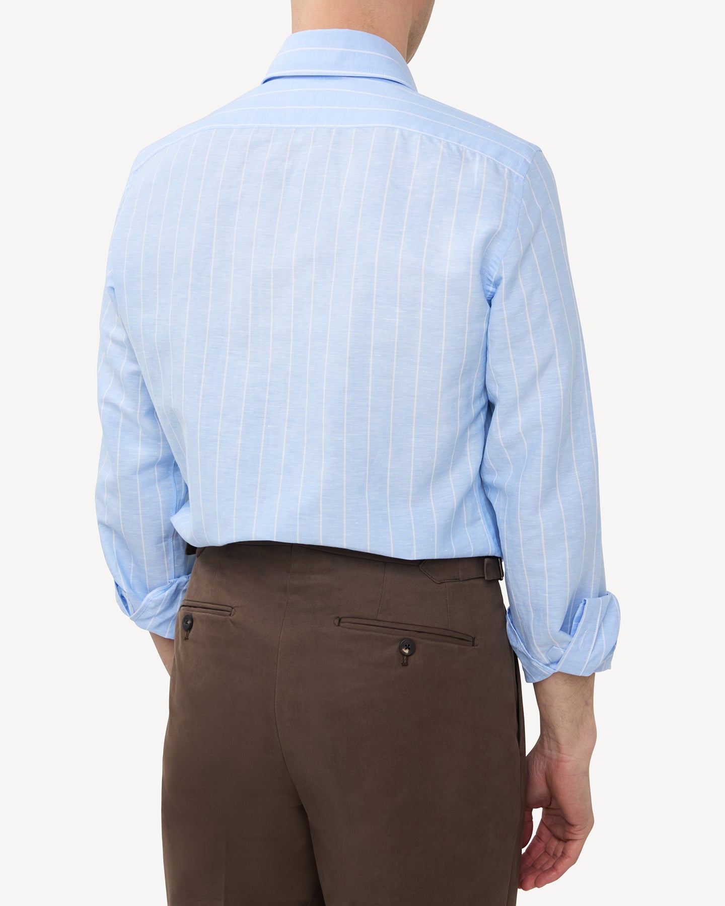 Man wearing a light blue reverse stripe cotton linen shirt and tobacco cotton trousers