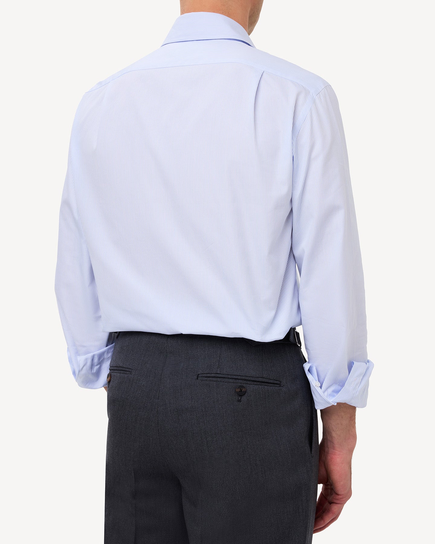 Man wearing a light blue hairline stripe poplin shirt with knife pleats in the back