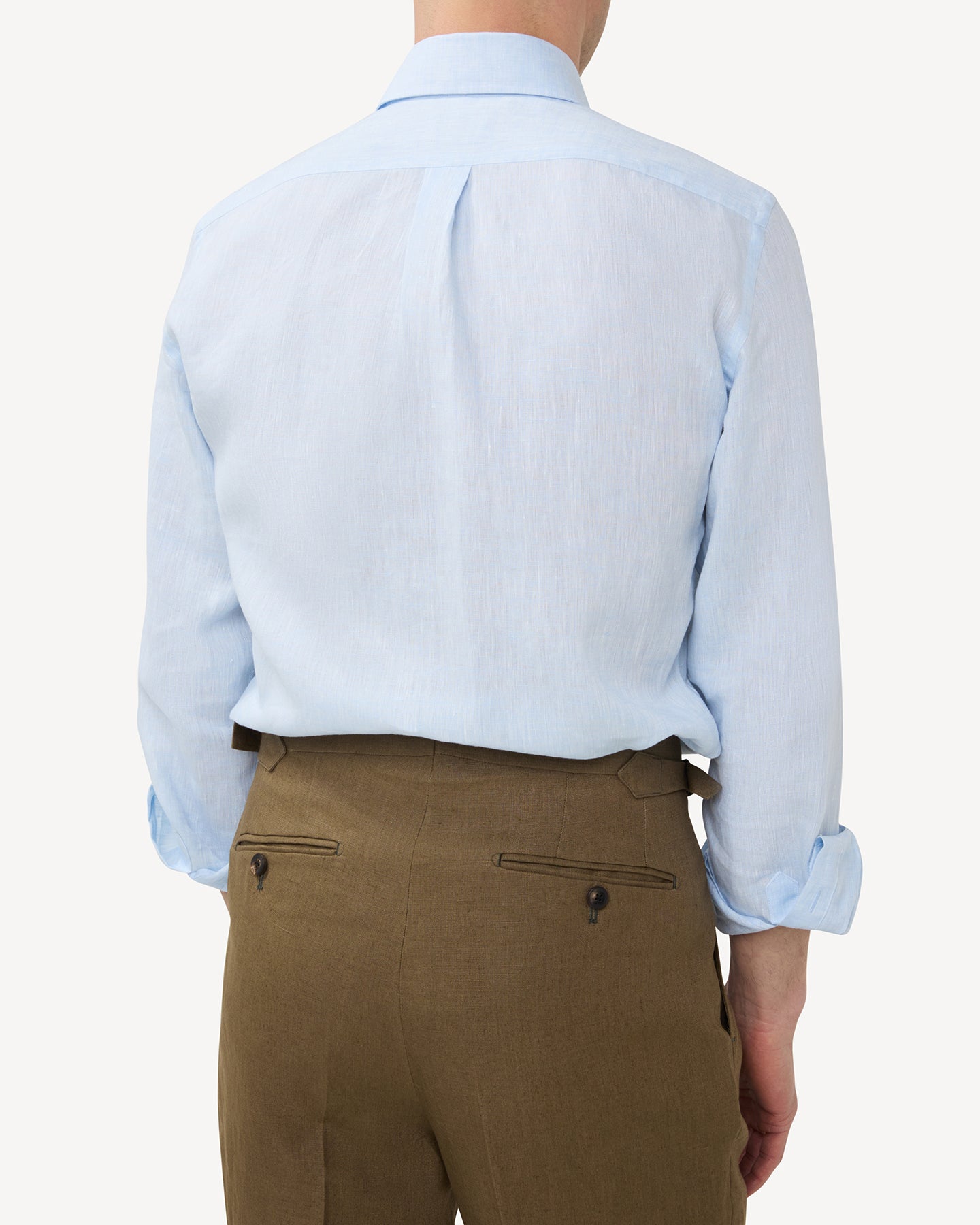 Man wearing light blue linen shirt and olive brown linen trousers