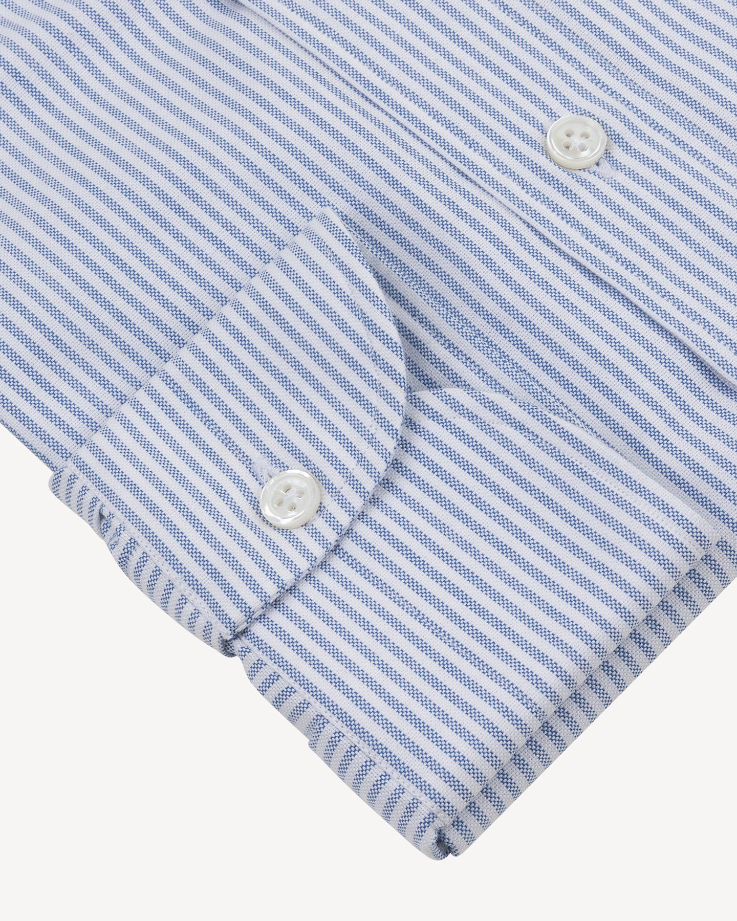 Close-up of the cuff of a blue and white striped shirt