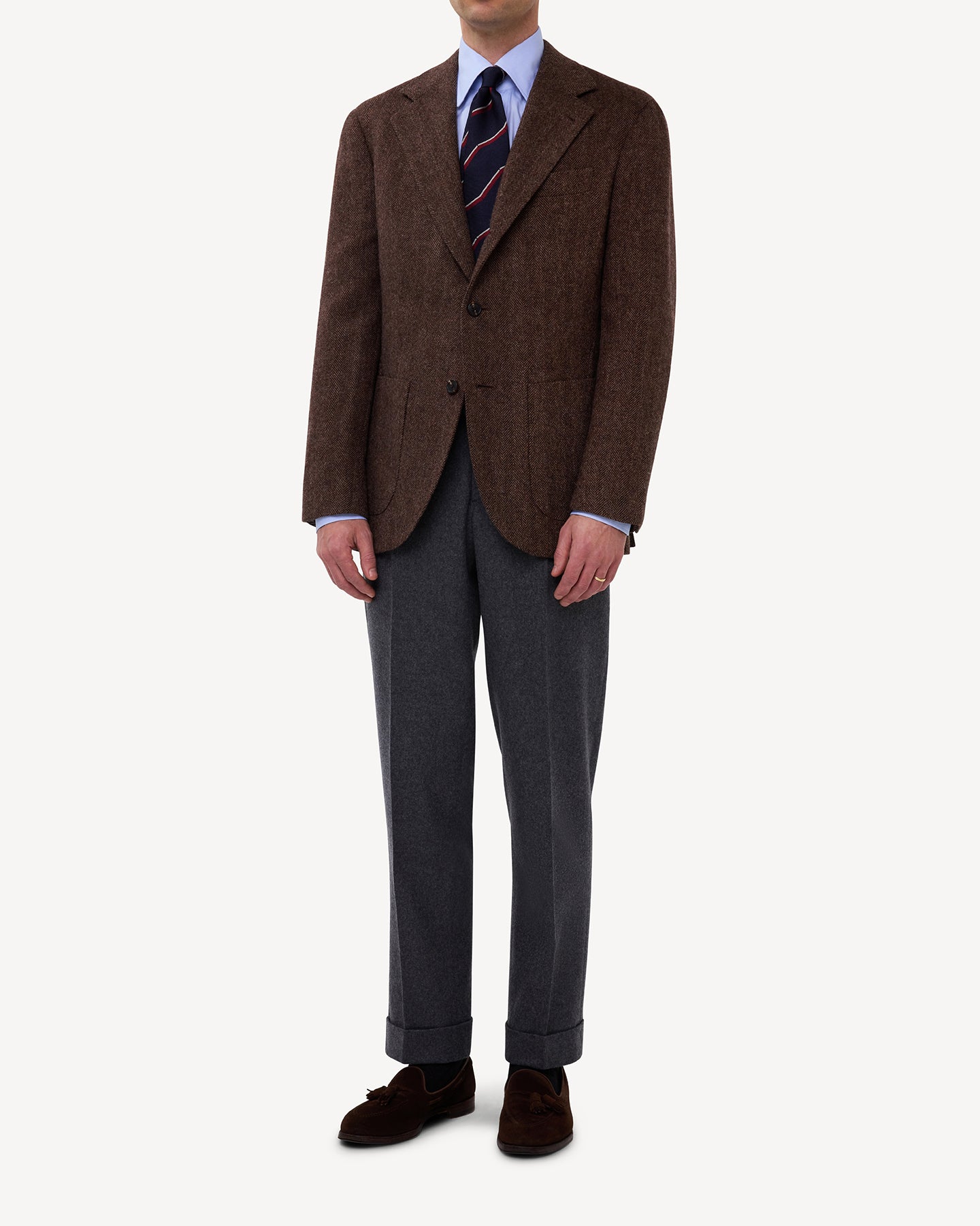 A man wearing a Brown Herringbone Tweed Sport Coat with flannel trousers and repp tie