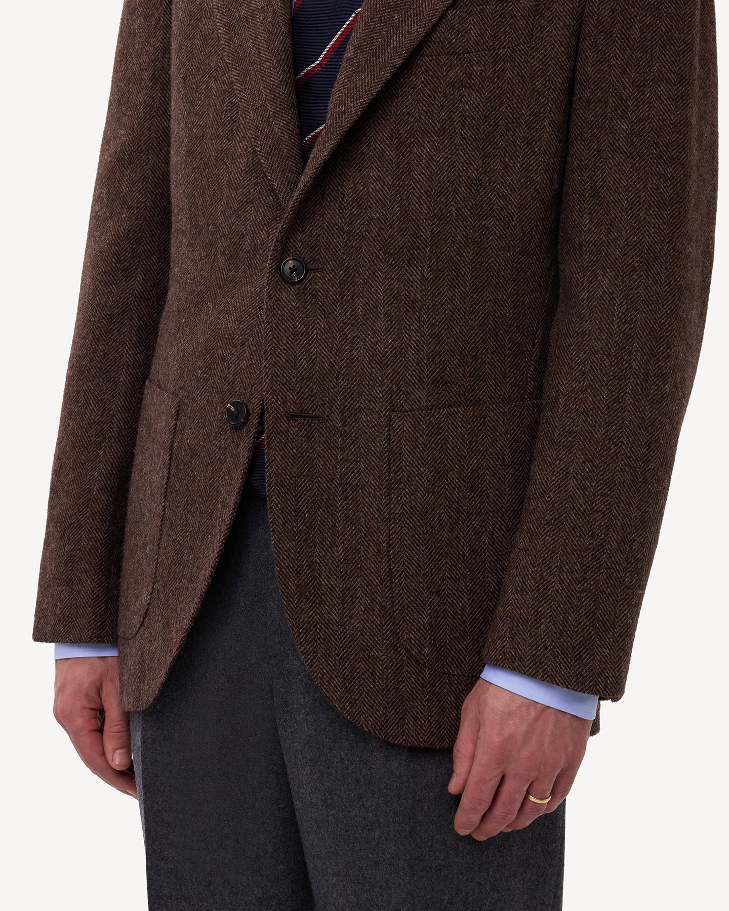 A man wearing a brown herringbone tweed sport coat with patch pockets