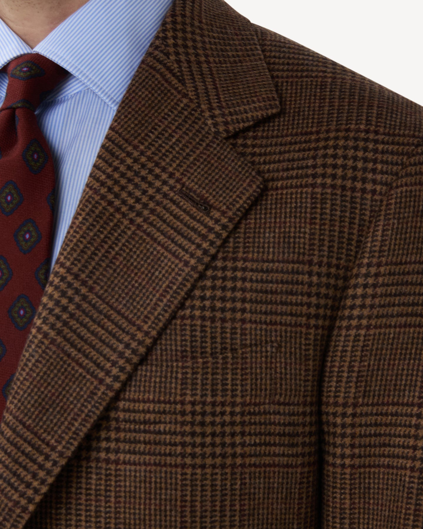 A man wearing a Brown Prince of Wales Merino Wool Sport Coat with notch lapels and handmade buttonhole