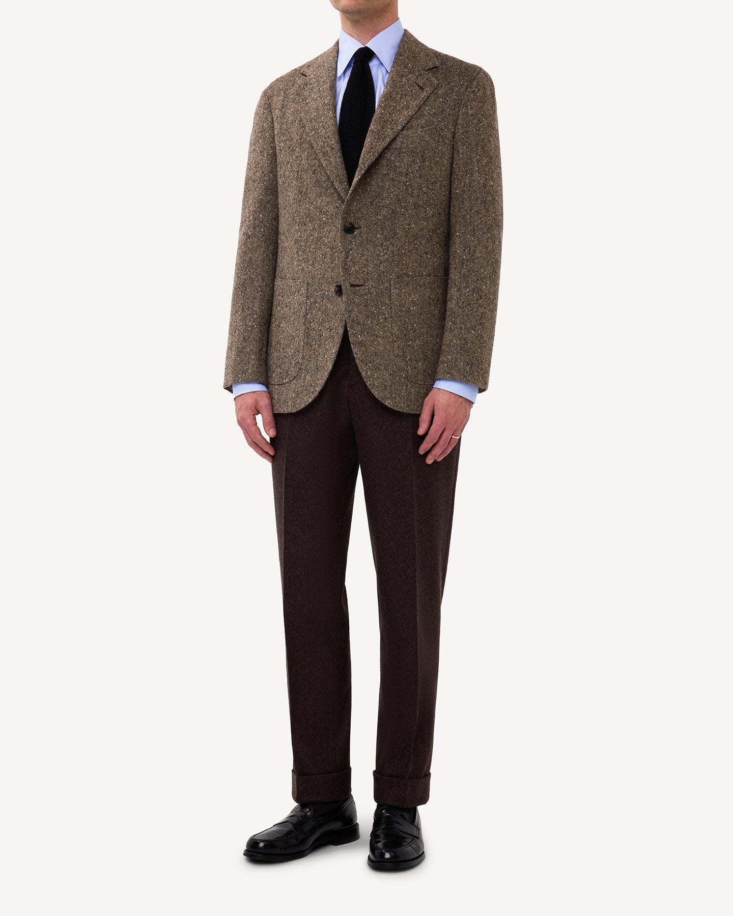 A man wearing a light brown Donegal tweed suit with dark grey cavalry twill trousers