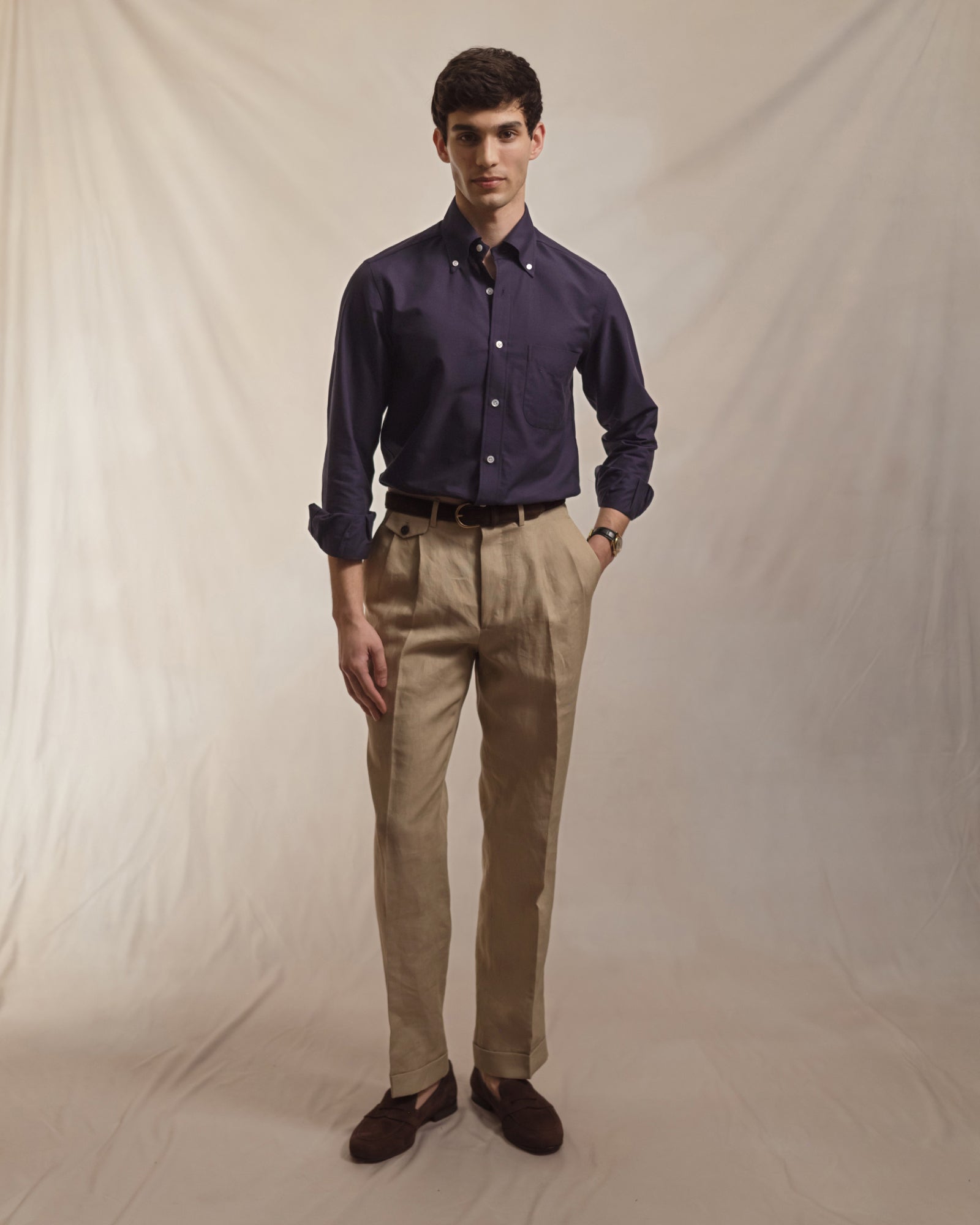 Man wearing a navy OCBD, taupe linen trousers and brown suede penny loafers