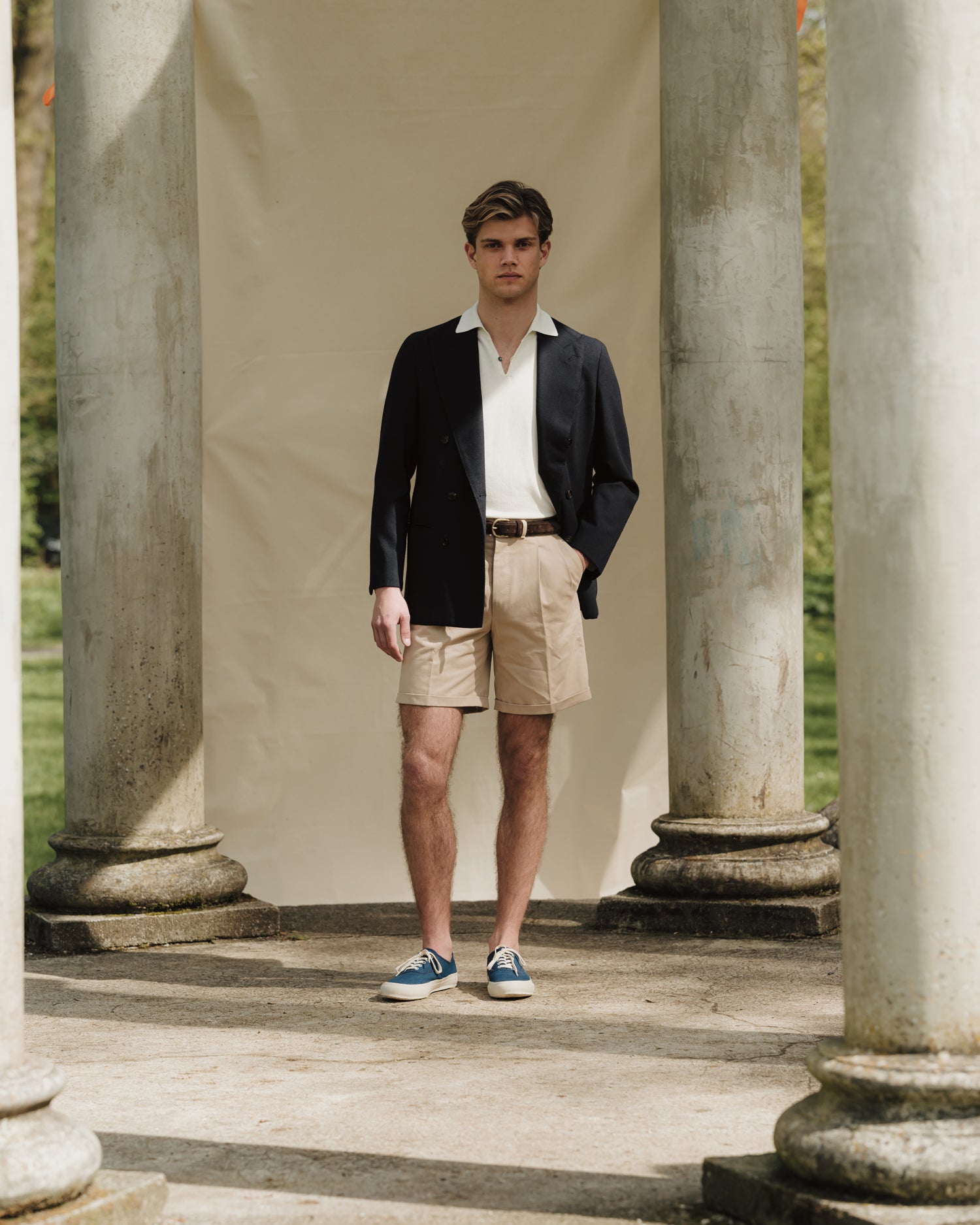 Man wearing stone cotton drill shorts, white skipper polo and navy double breasted jacket