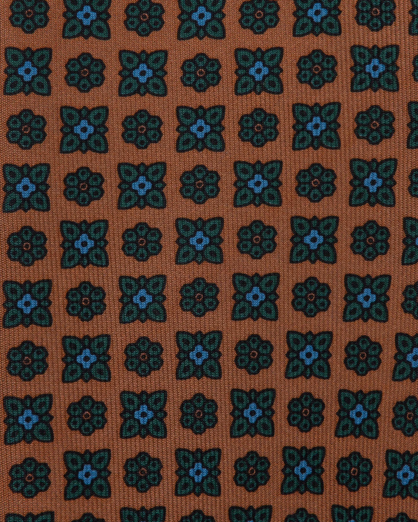 Burned orange Ancient Madder tie with small floral pattern in shades of light blue, teal, and black.