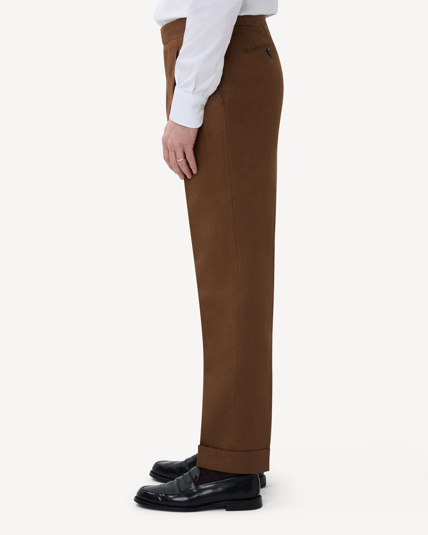 The side of dark tan linen trousers with single pleats and side adjusters
